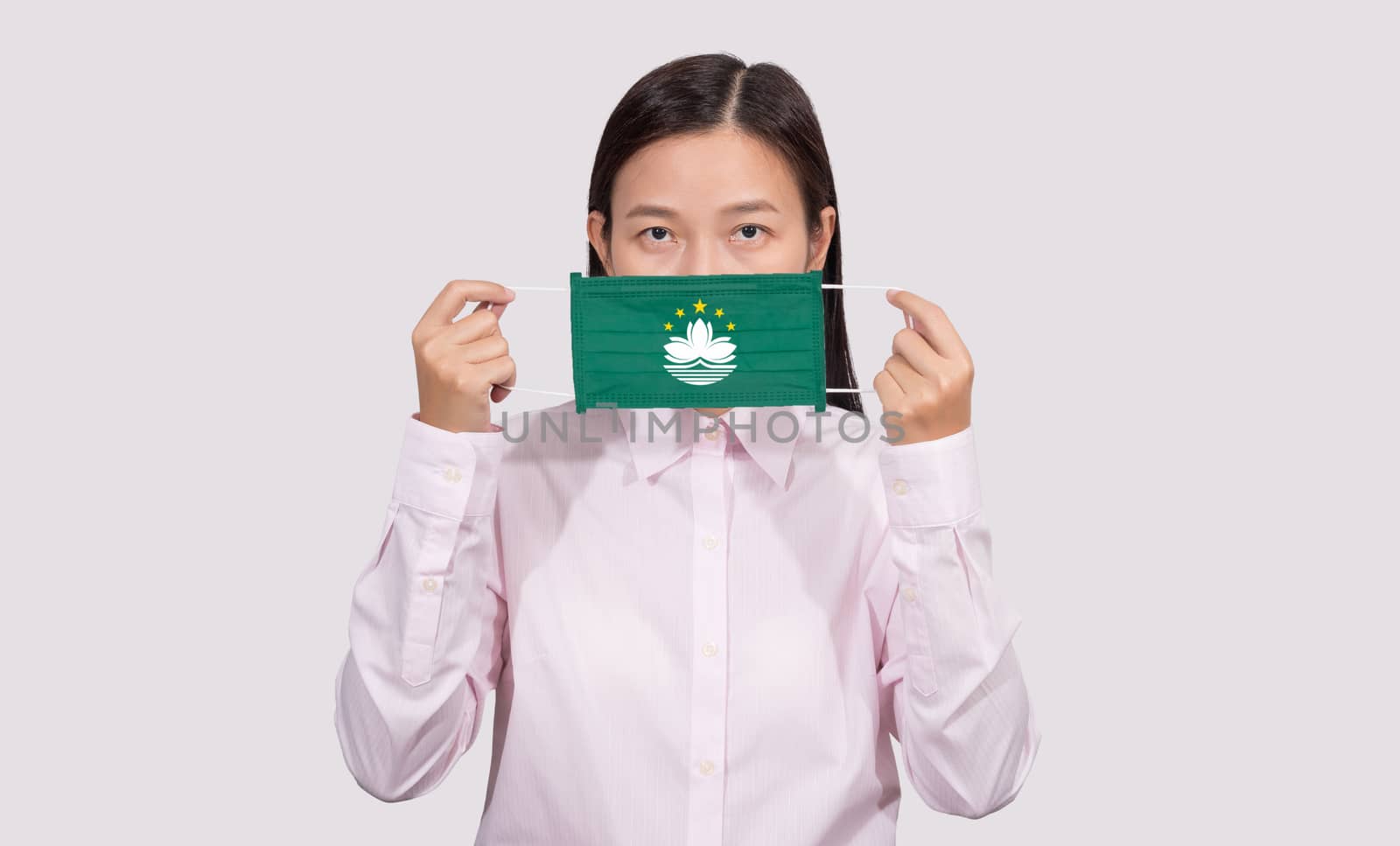 Asian woman wearing hygienic face mask painting Macau flag to protect from the Coronavirus 2019 (COVID-19) infection outbreak situation, the virus originated from Wuhan, China.