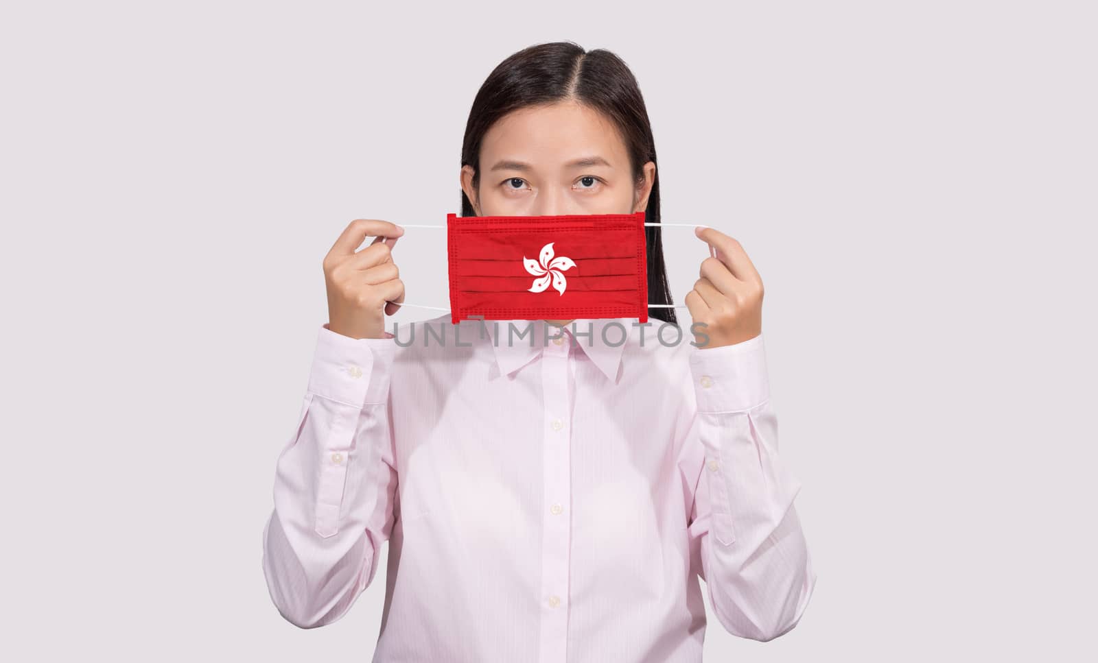 Asian woman wearing hygienic face mask painting Hong Kong flag to protect from the Coronavirus 2019 (COVID-19) infection outbreak situation, the virus originated from Wuhan, China.