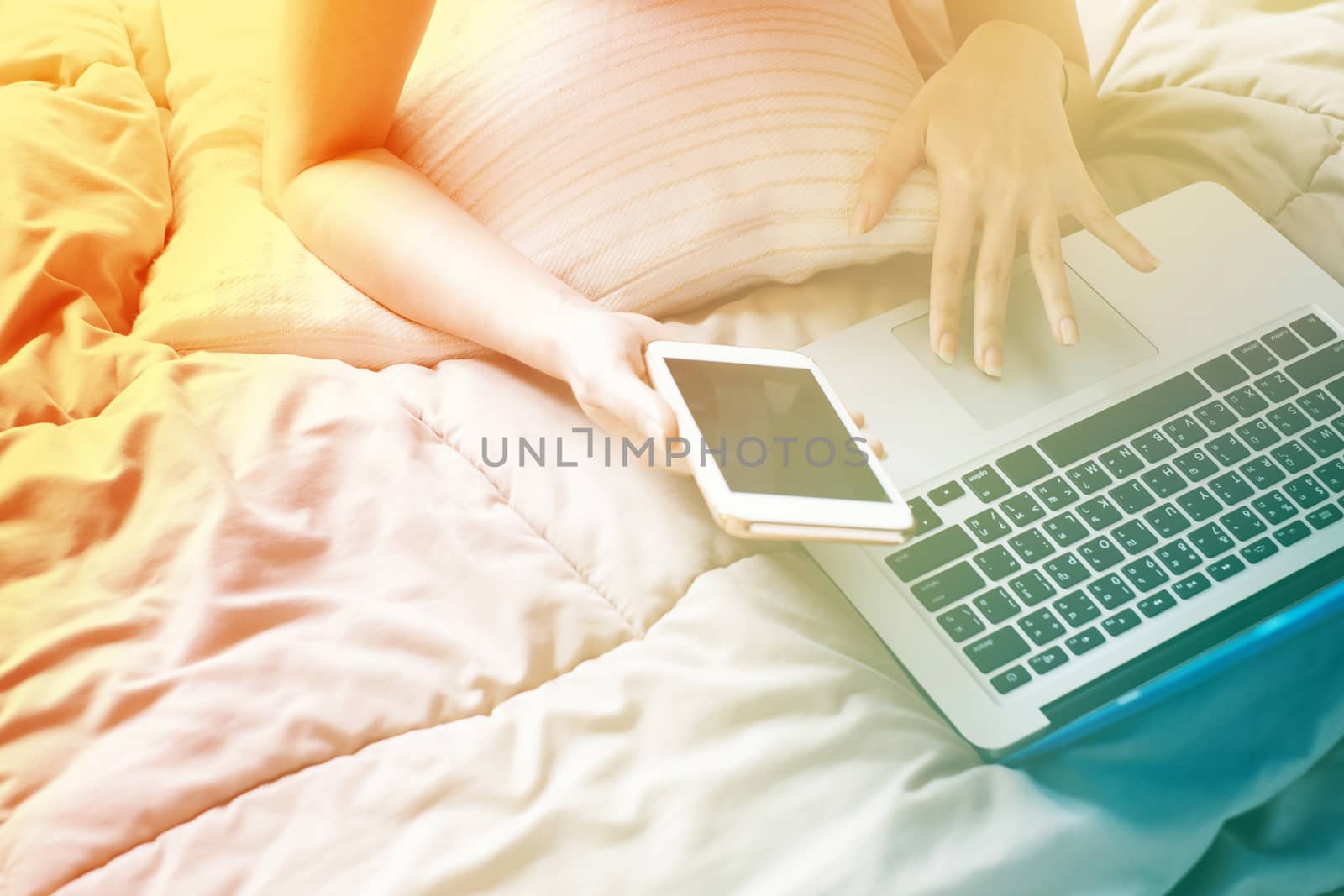 Close up Woman lying on bed with a laptop computer and smartphone on the lazy day, color transition style and gradient color 