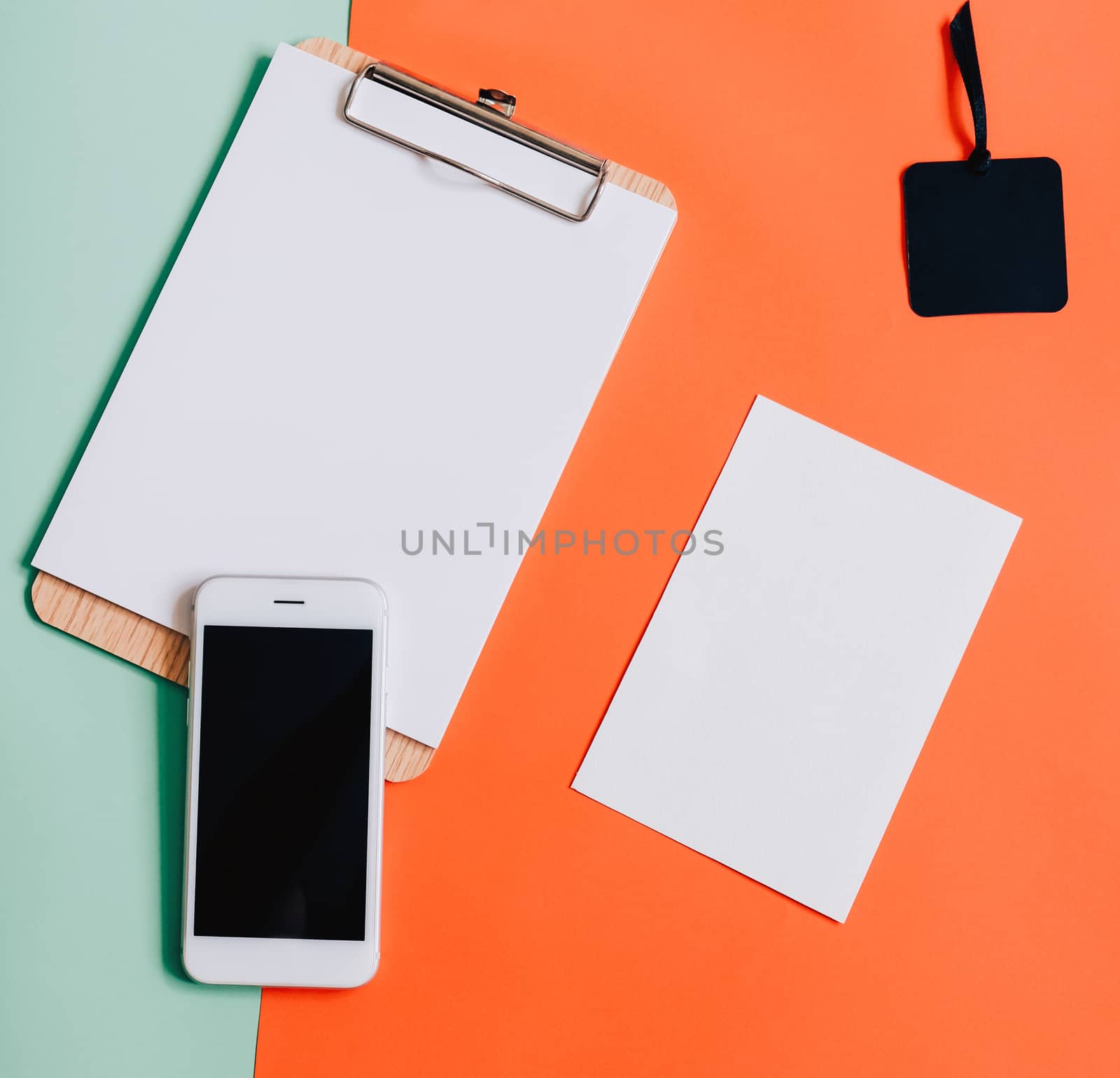 Creative flat lay of smartphone, blank clipboard and white card  by nuchylee