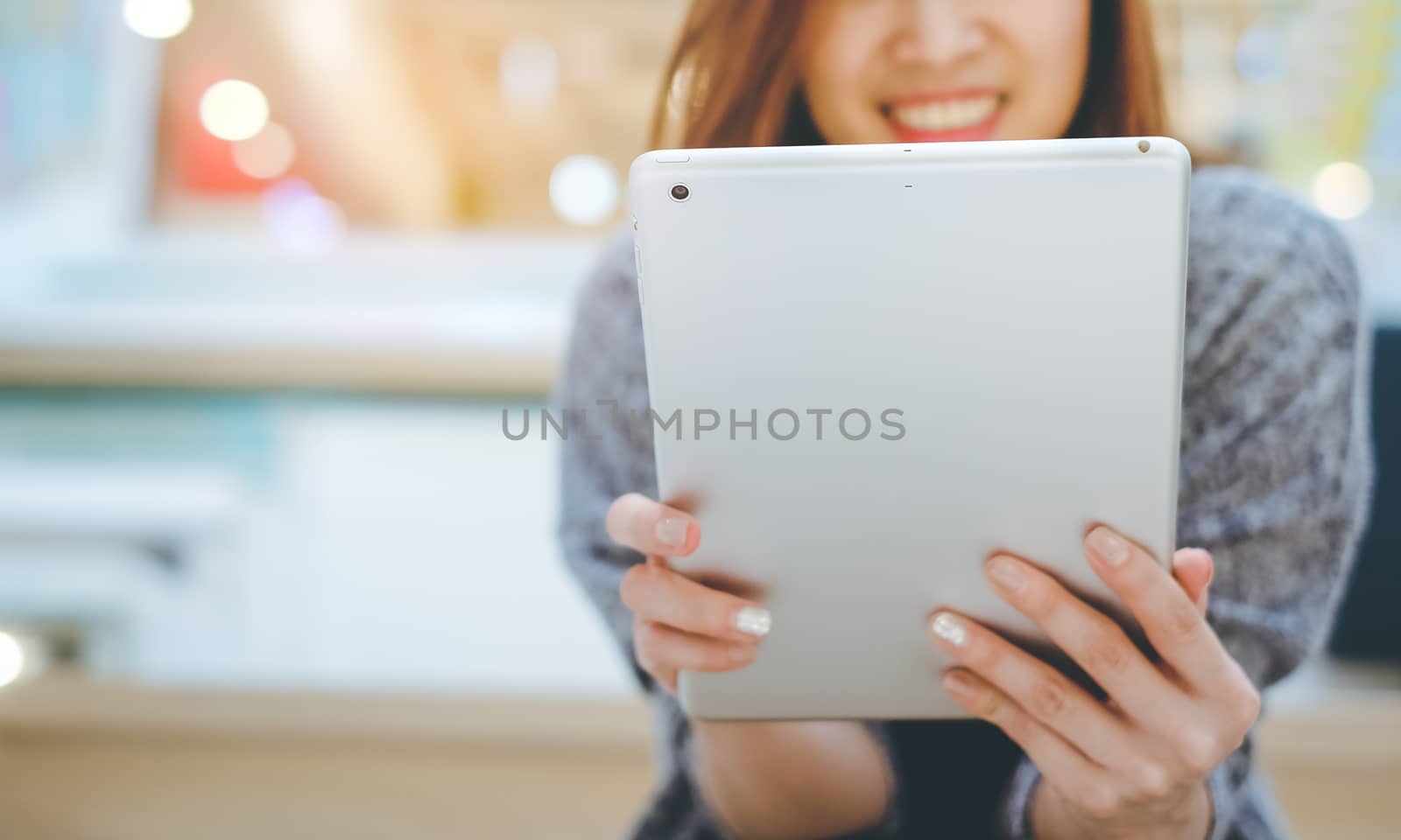 Young asian woman smiling and using tablet in modern office or shopping mall