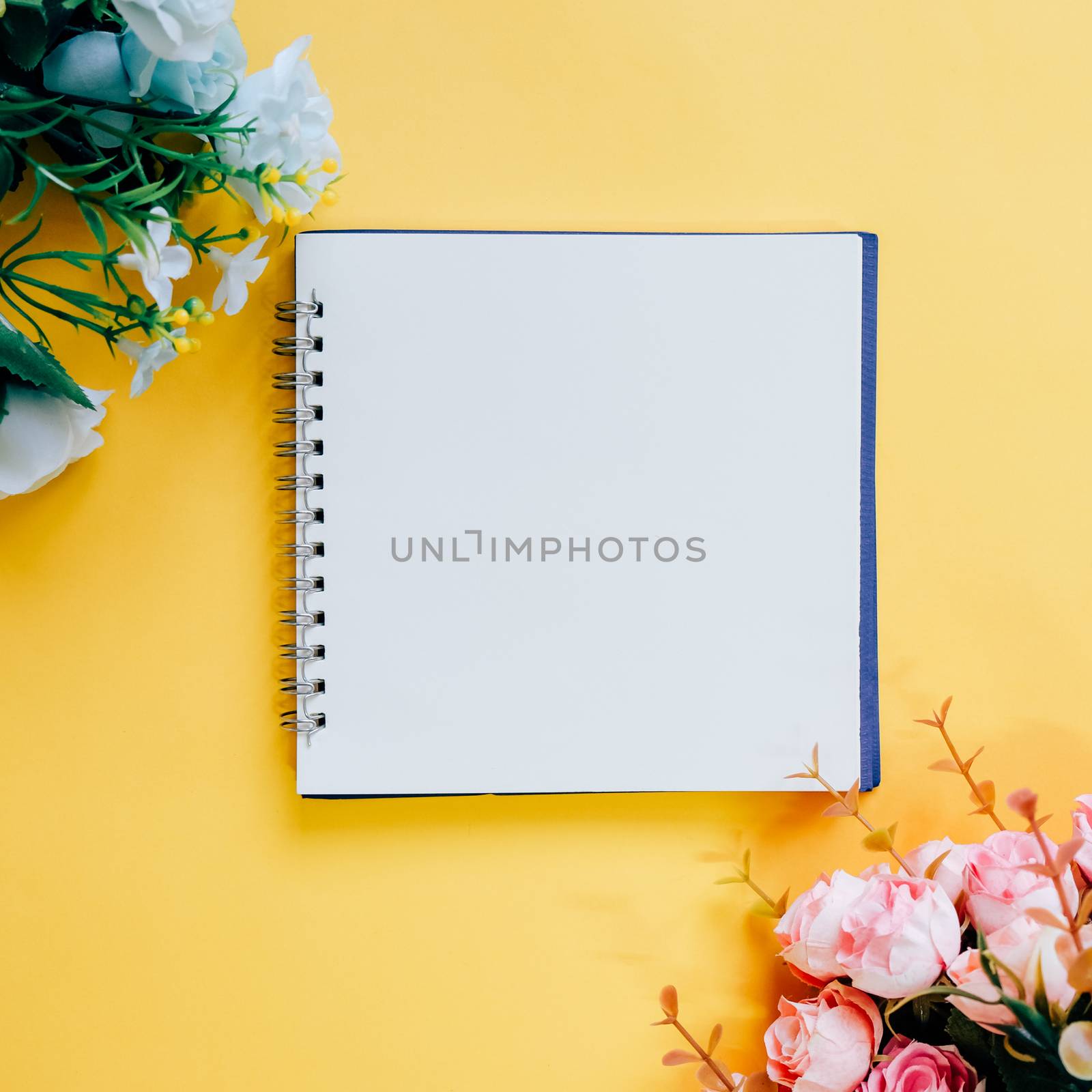 Flat lay of minimal workspace blank notebook with flower on yell by nuchylee