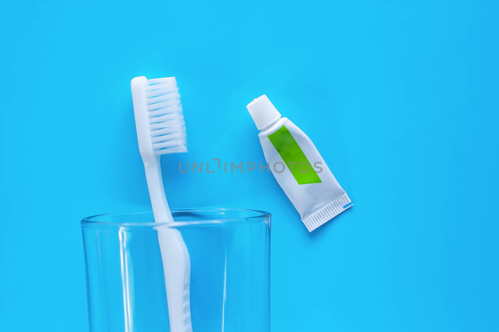 White toothbrush in the transparent glass with toothpaste by iamnoonmai