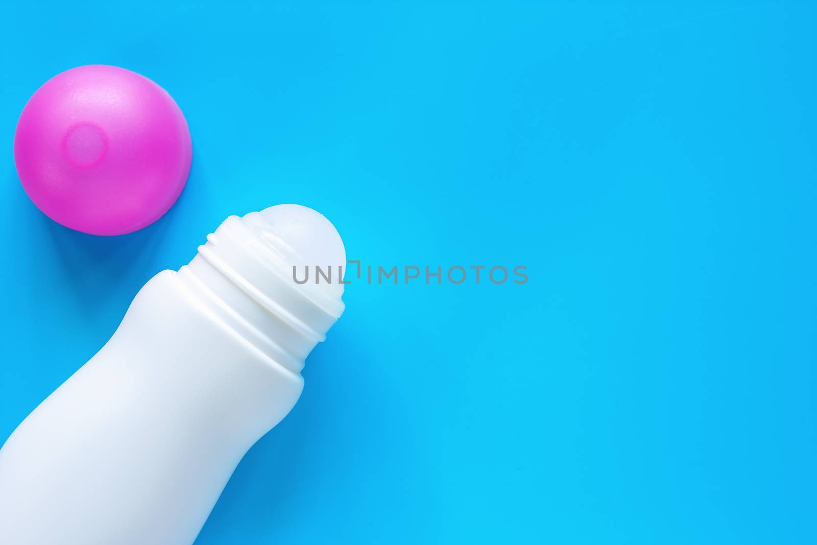 Female deodorant or roll on bottle with pink cover on blue background for body skin care concept