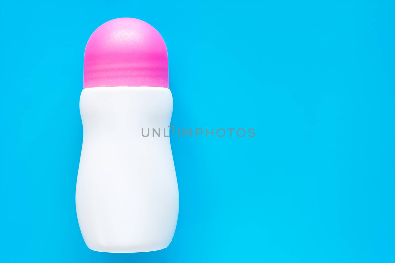 Female deodorant or roll on bottle with pink cover on blue background for body skin care concept