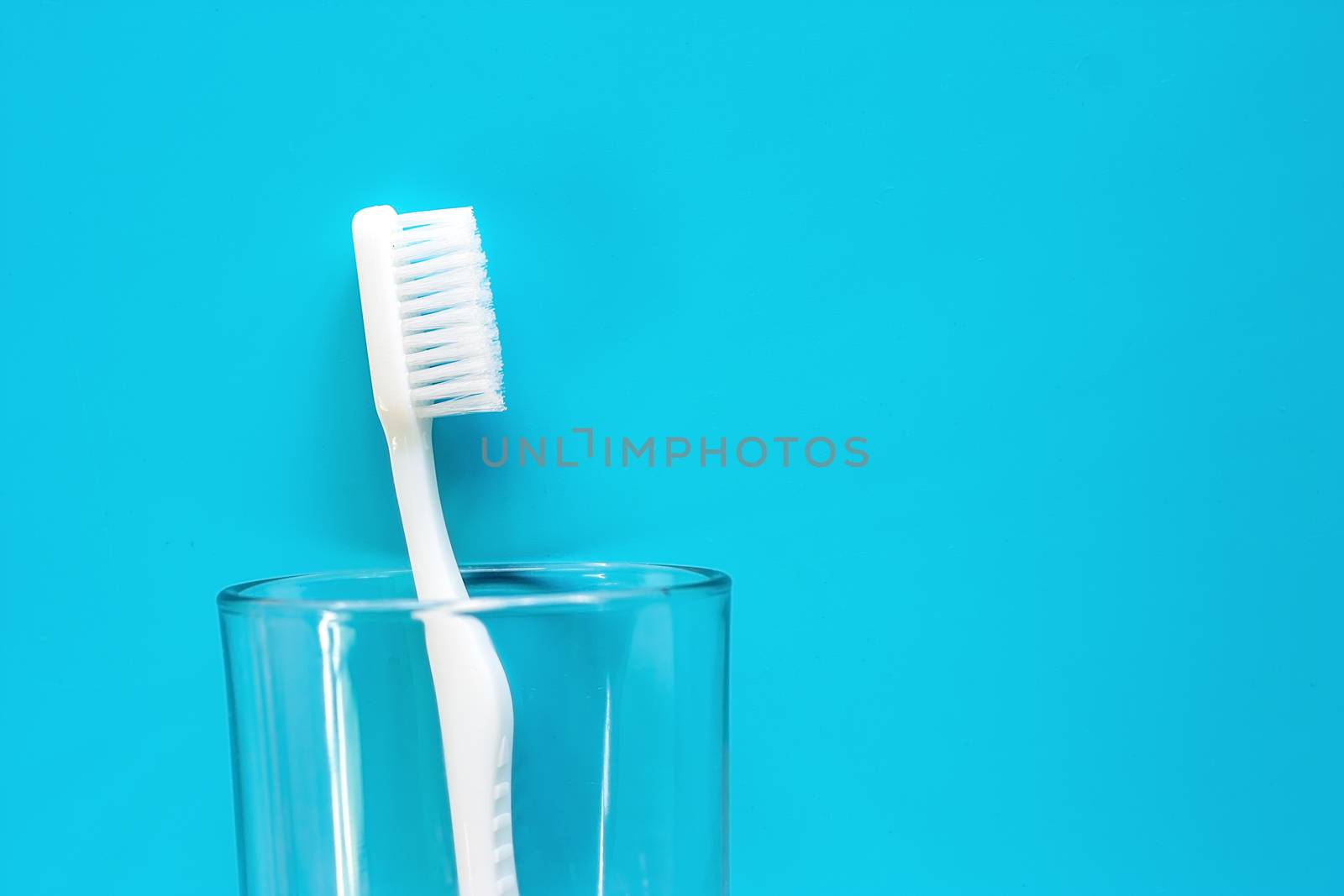 White toothbrush in the transparent glass by iamnoonmai