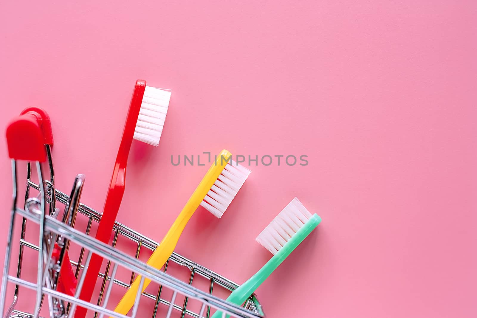 Shopping cart with toothbrush on pink background for market and dental care concept