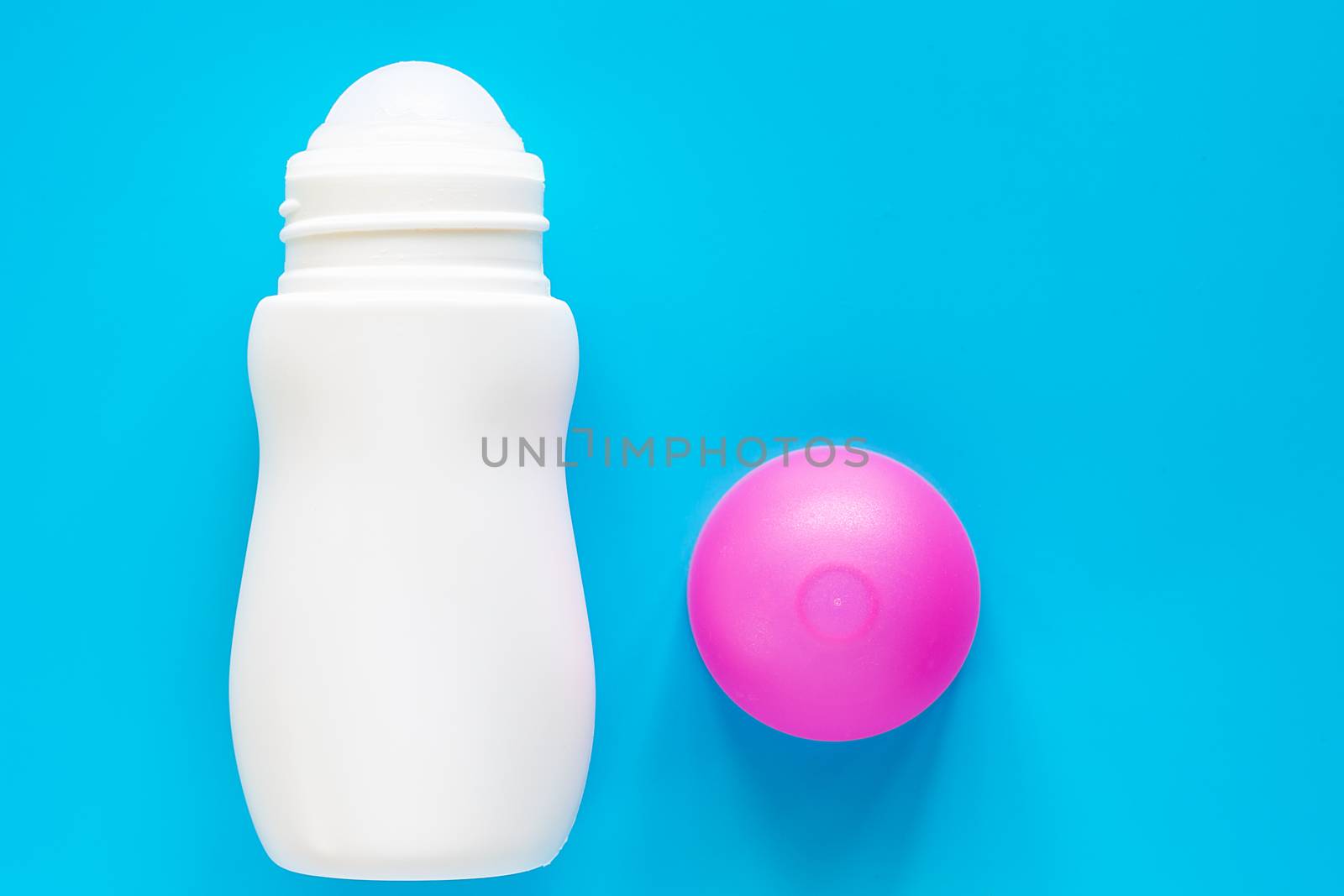 Female deodorant or roll on bottle with pink cover on blue background for body skin care concept