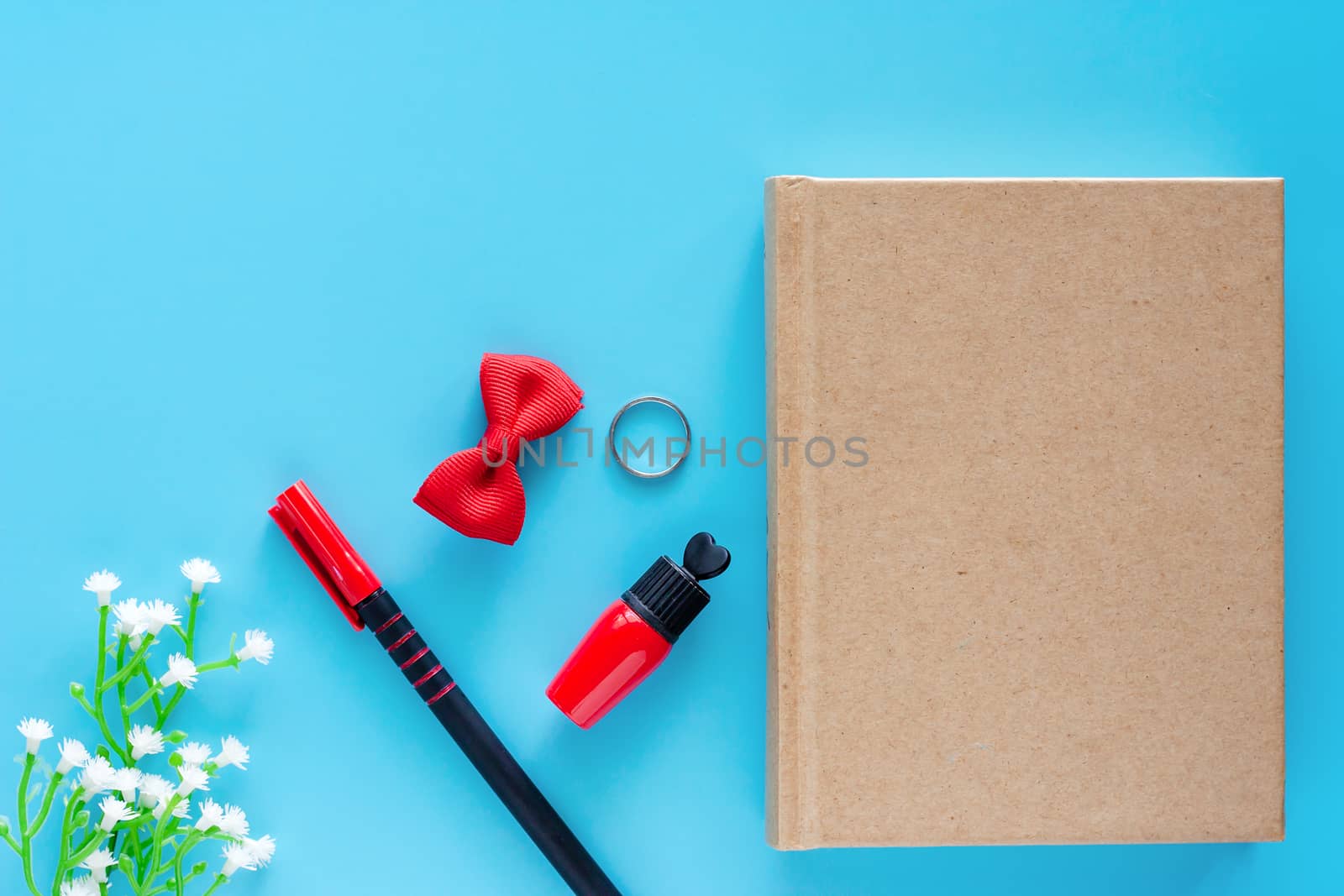 Top view of diary notebook with a pen, red lipstick and decorated items on blue background for lady lifestyle concept
