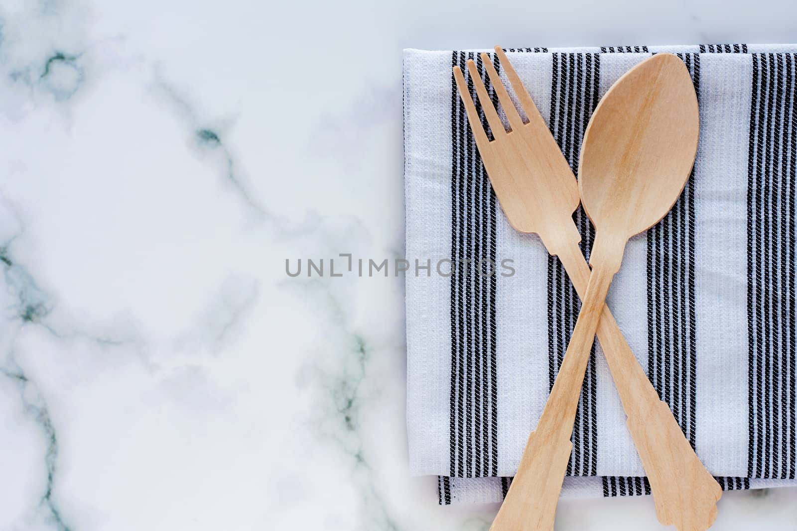 Wooden spoon and fork with napery on marble background for utensil and kitchenware concept