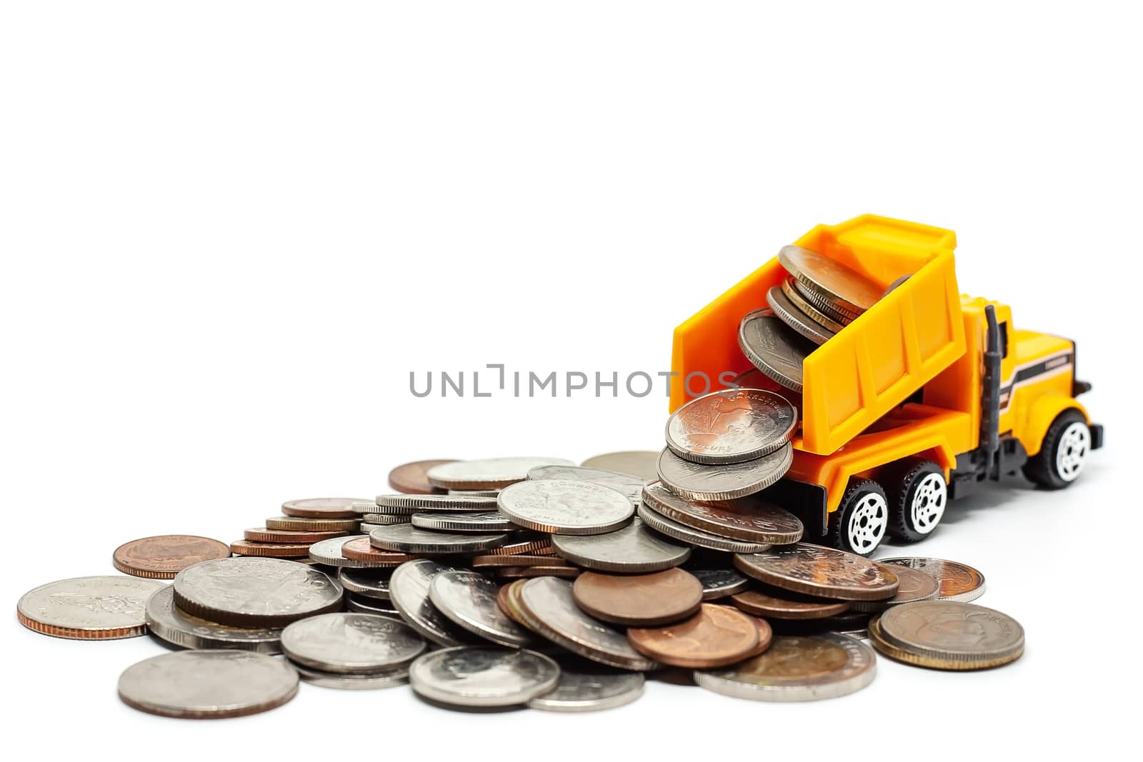 A yellow toy dump truck with pile of coins on white background for saving money, investment, business and finance concept