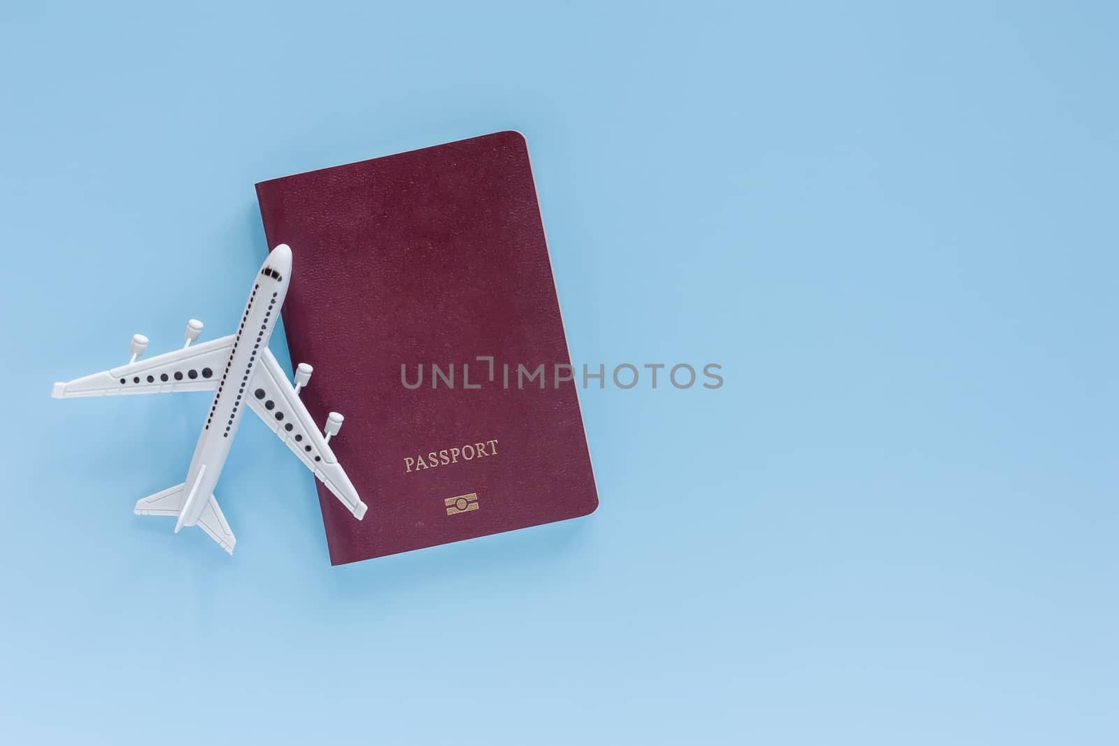 White airplane model with passport on blue background for travel and journey concept