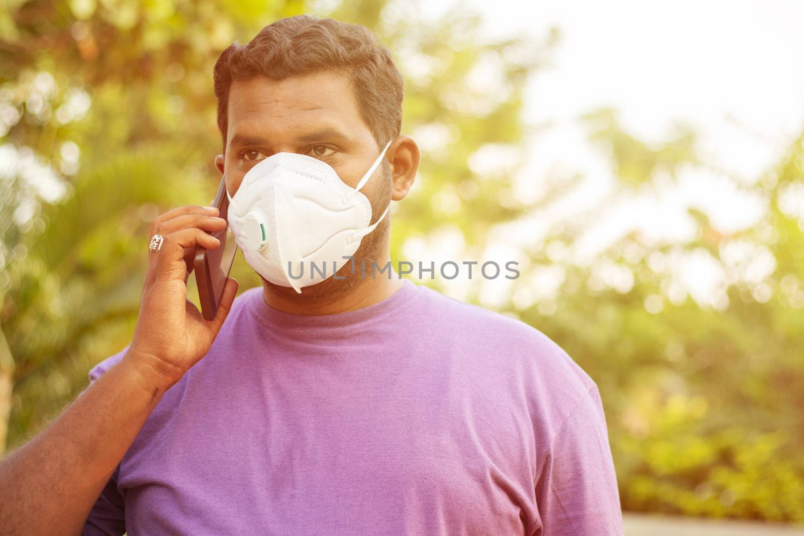 Concept of pollution, Radiation and healthcare - Young man talking on mobile with air Pollution mask, outdoor - Indian young adult with face mask to protect from polluted smog