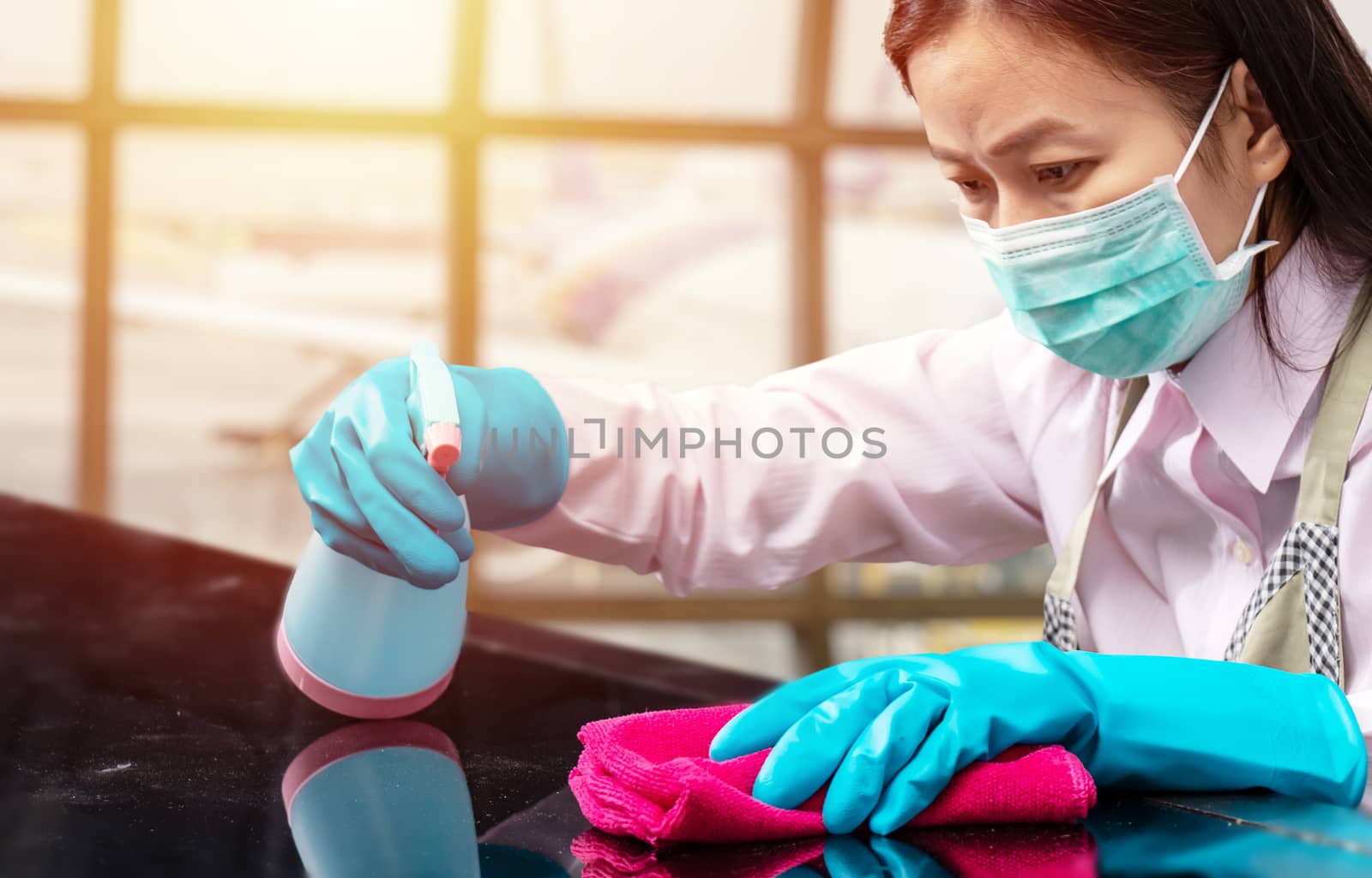 airport staff wearing hygienic face mask and blue rubber glove holding pink microfiber cleaning cloth and spray bottle with sterilizing solution make cleaning and disinfection for good hygiene around airport