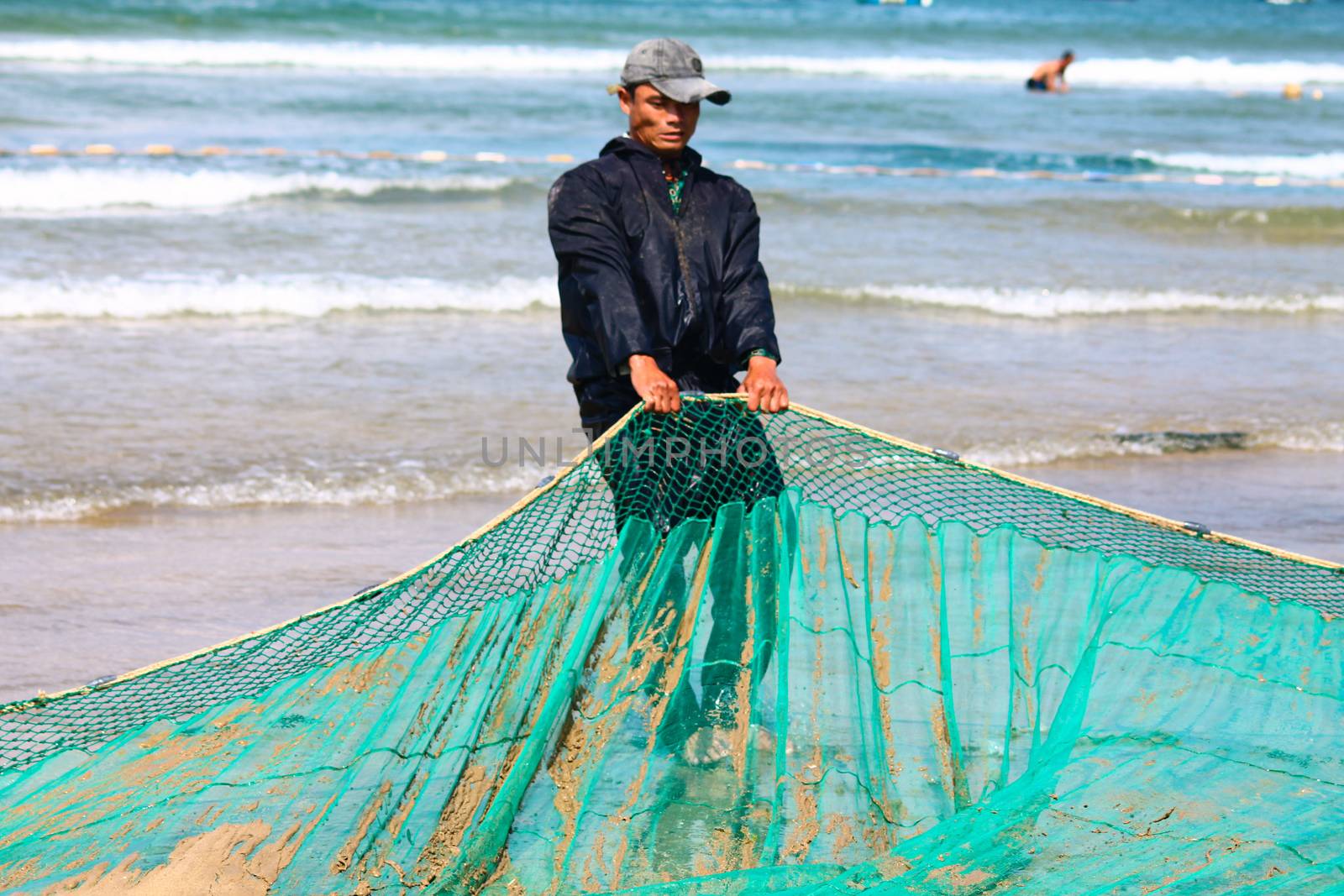 Editorial. Vietnamese fisherman pulling the nets back to shore in the fishing village of Quy Nhon