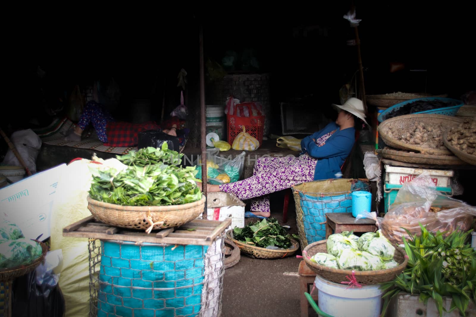 Editorial. A Khmer or Cambodian vegetable seller taking a nap in her market stall in the local market of Phnom Pehn, Cambodia