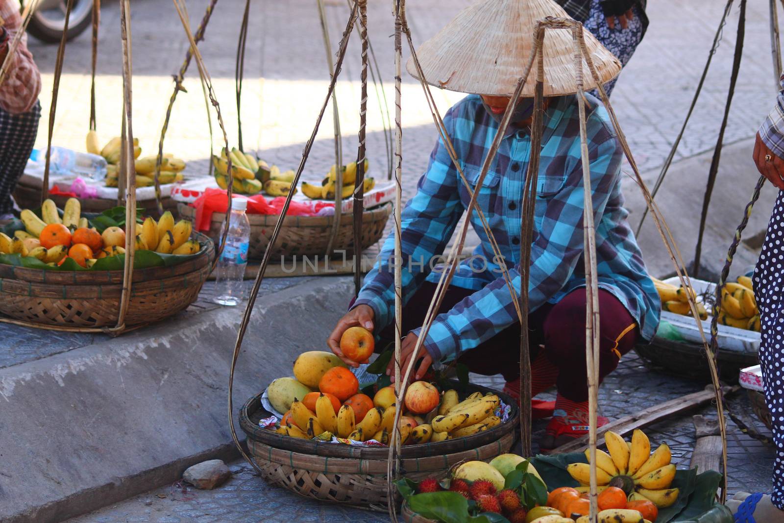 Editorial. Vietnamese street vendors selling fruits using a carrying pole in the ancient town of Hoi an, Vietnam