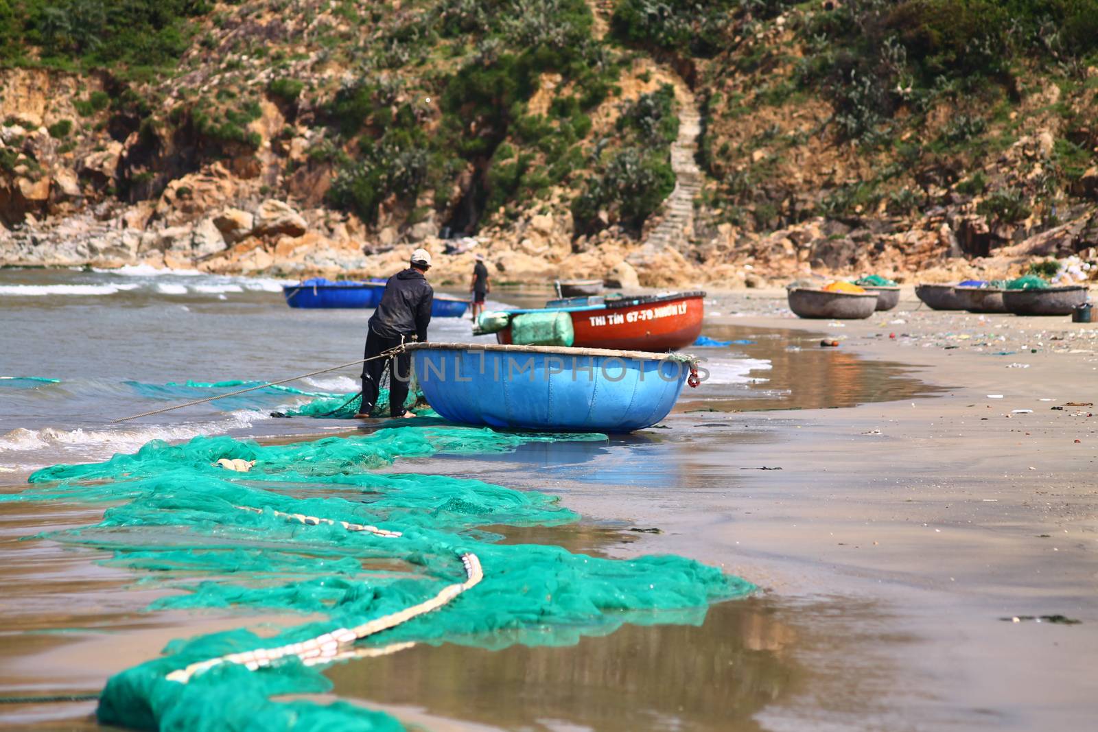 Editorial. Vietnamese fisherman pulling the nets back to shore in the fishing village of Quy Nhon in Vietnam