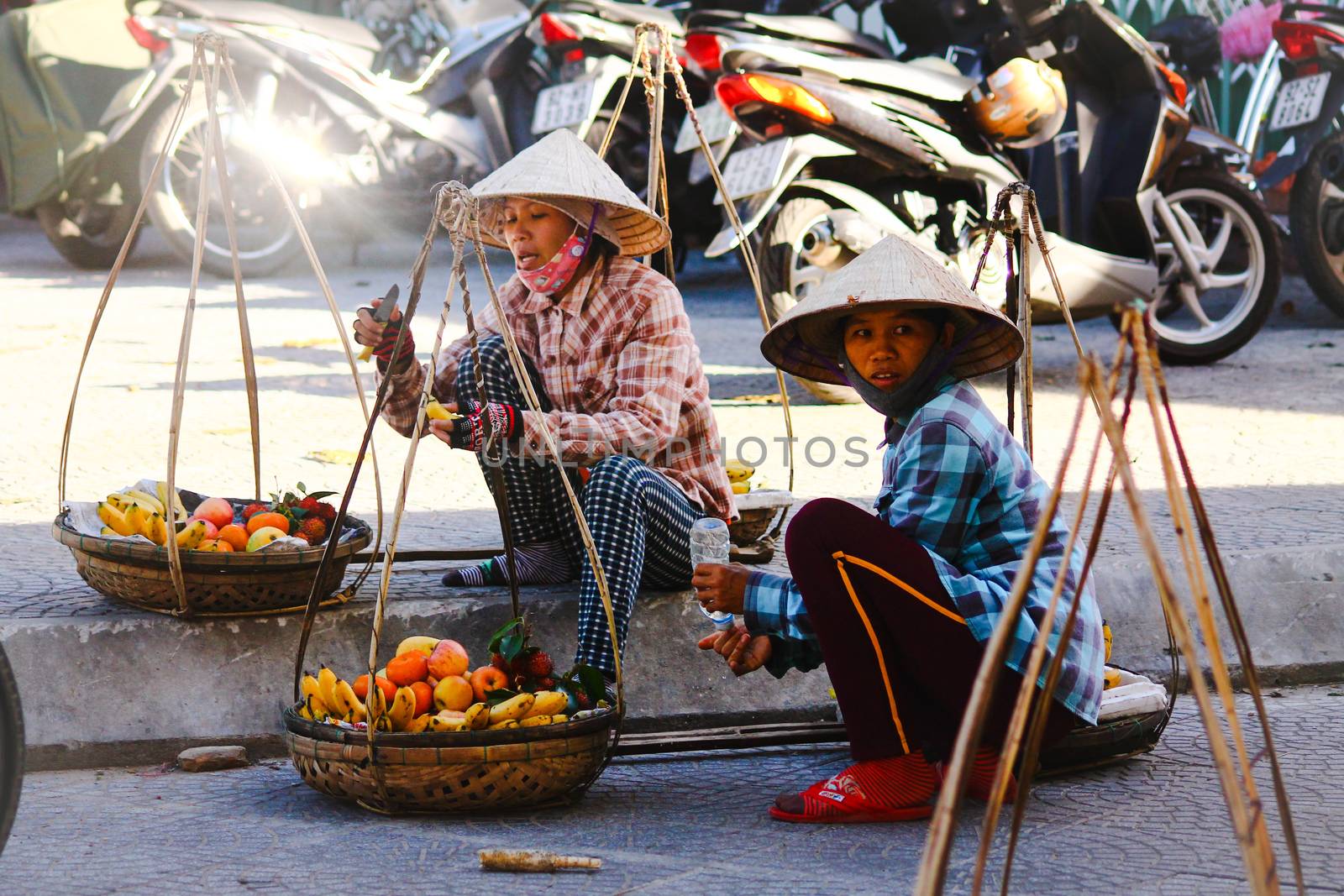 Editorial. Vietnamese street vendors selling fruits using a carrying pole in the ancient town of Hoi an, Vietnam