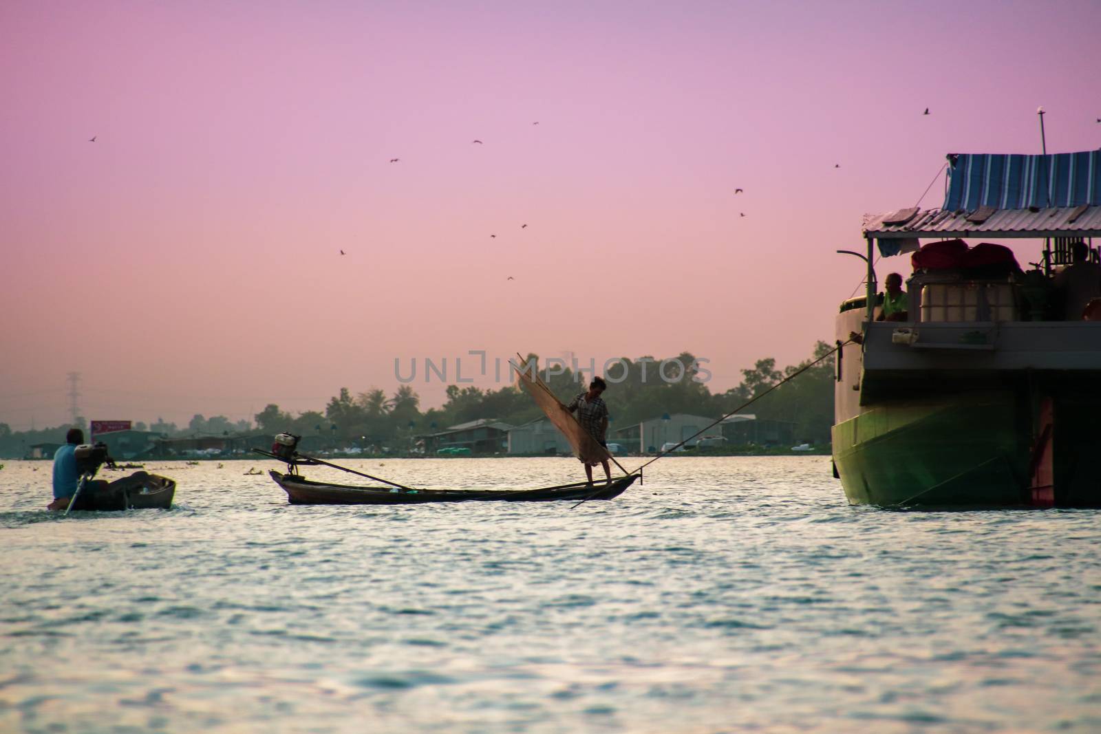 A fisherman on his boat along the Mekong River during the sunset