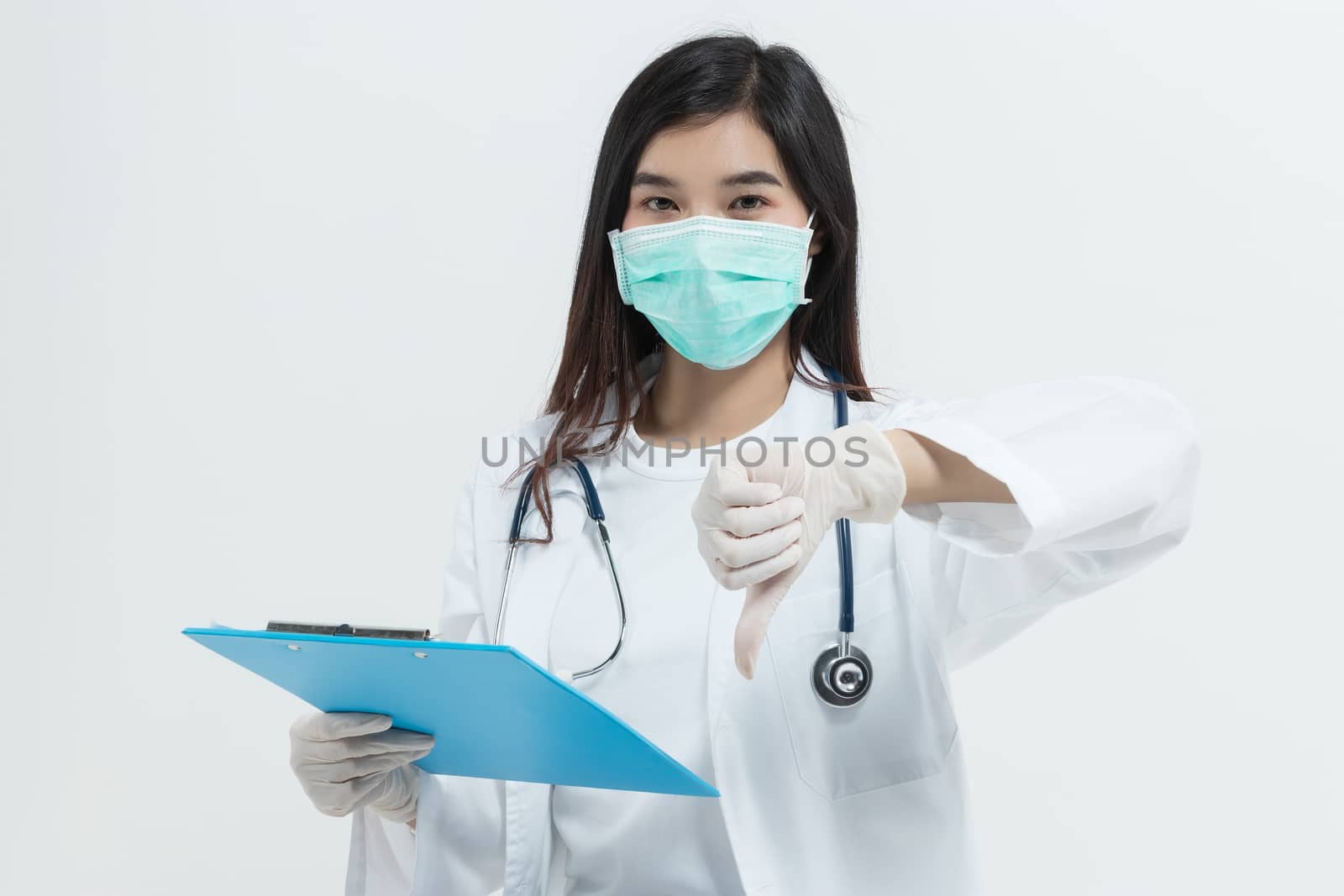 young Asian doctor woman wearing doctor gown uniform coat , medical mask and stethoscope holding a clipboard looking unhappy and angry showing rejection and negative with thumb down gesture.