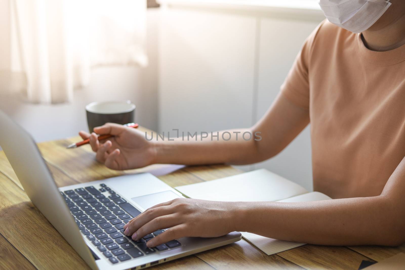 Woman working from home wearing protective mask. COVID-19 Pandemic Coronavirus home isolation auto quarantine wearing face mask protective for spreading of disease virus SARS-CoV-2. Working from home and Cleaning hands with sanitizer gel.