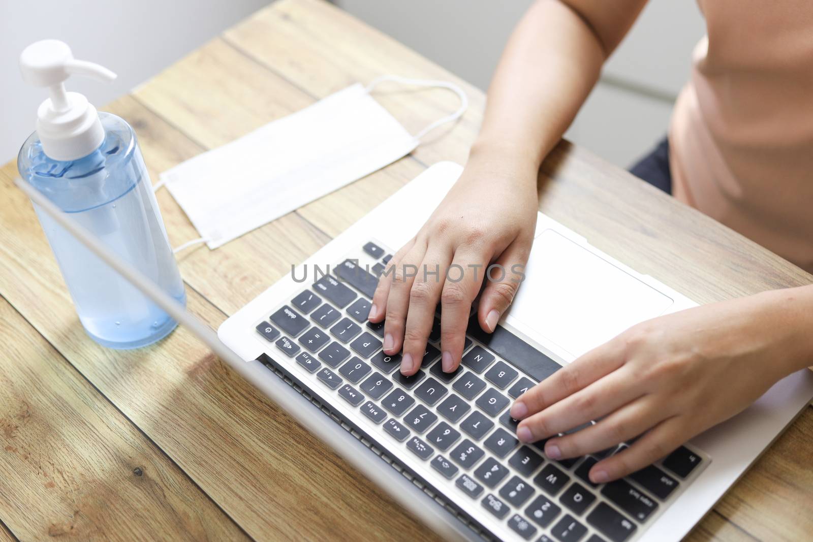 Woman working from home wearing protective mask. COVID-19 Pandemic Coronavirus home isolation auto quarantine wearing face mask protective for spreading of disease virus SARS-CoV-2. Working from home and Cleaning hands with sanitizer gel.