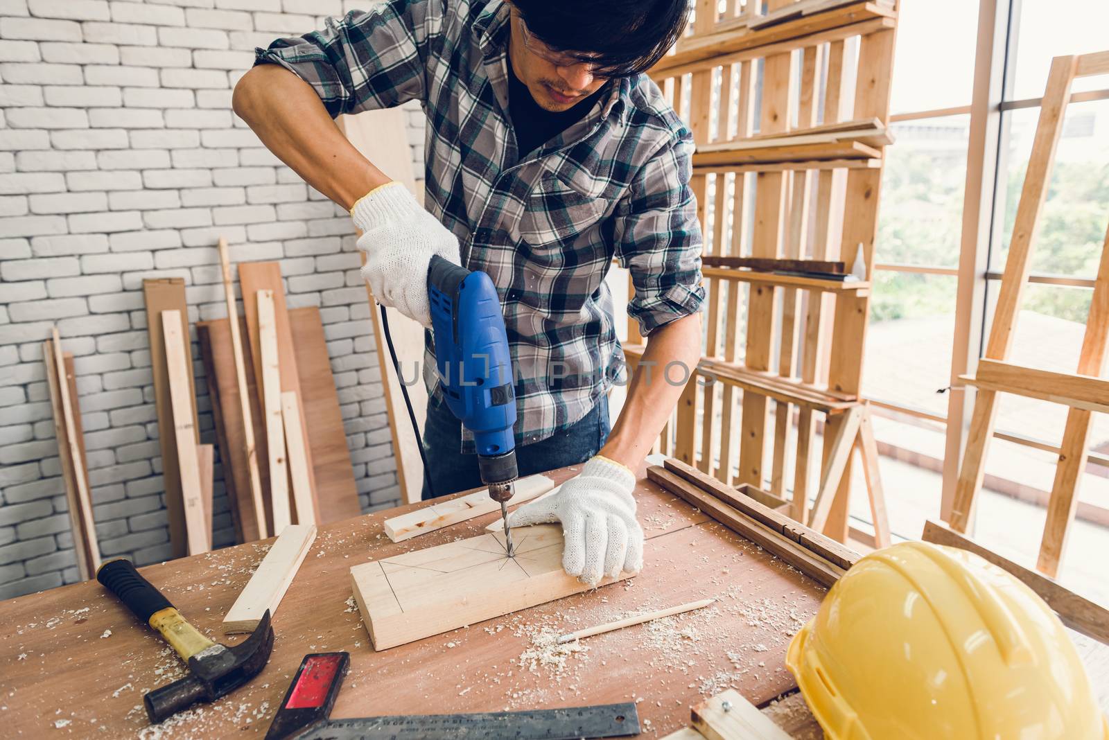 Carpenter Man is Working Timber Woodworking in Carpentry Shop, Craftsman is Screw Coring Timber Frame for Wooden Furniture in Workshop. Workmanship and Job Occupation Concept