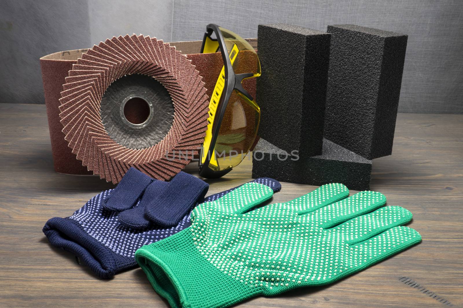 Various grinding tools - sanding belt, clamps, abrasive sponge and flap disc for angle grinder, safety gloves and goggles, renovation, safety and health at work concept