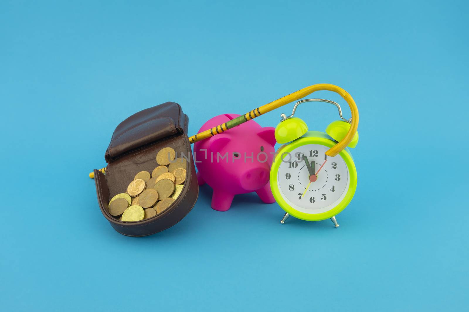 Saving for old-age and retirement concept with open purse with coins, walking stick, alarm clock and piggy bank over a blue background with copy space