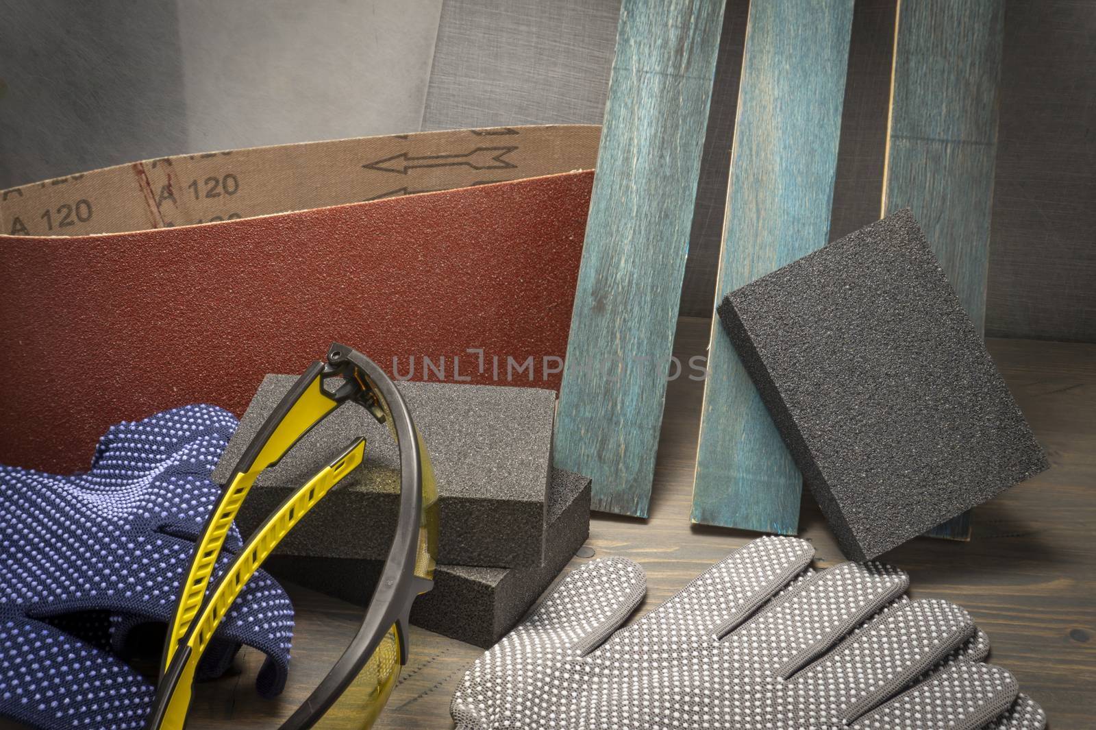 Various grinding tools - sanding belt, abrasive sponge and flap disc for angle grinder, safety gloves and goggles, renovation, safety and health at work concept