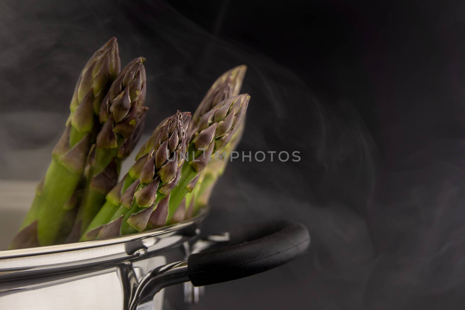 Fresh green asparagus spears in a metal pot with steam in close up conceptual of gourmet eating in spring