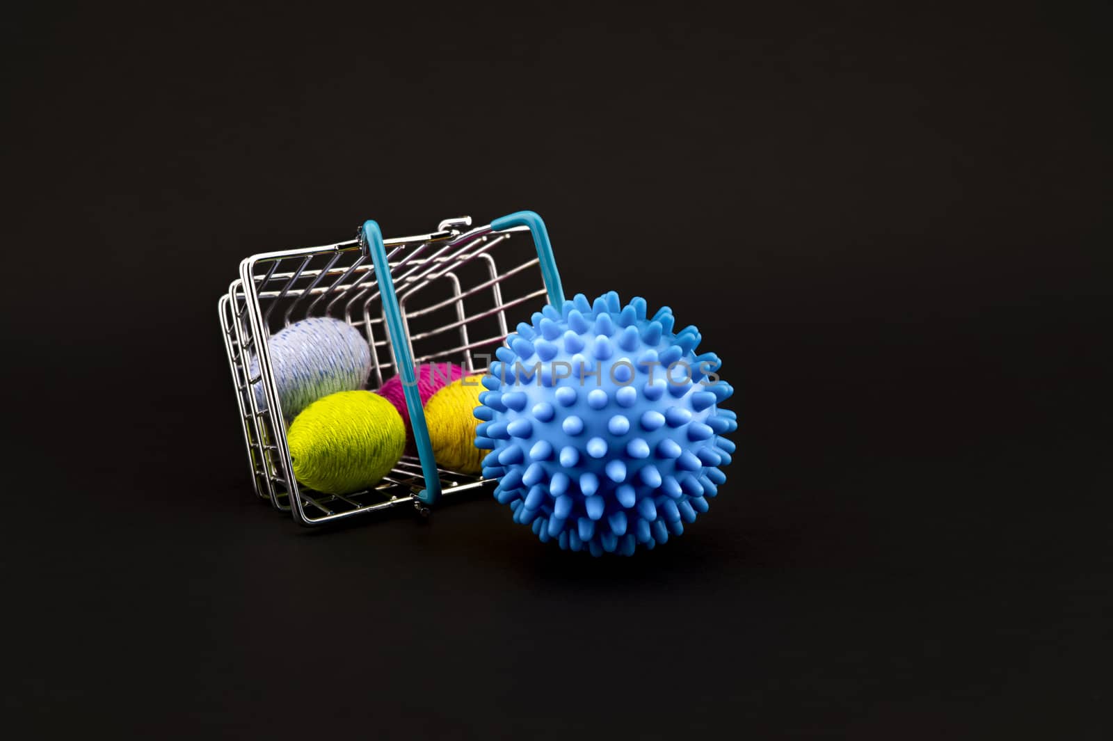 Blue virus molecule, shopping basket and creative colorful eggs made from yarn conceptual of the possibility of infection with corona virus or Covid-19 over a black background