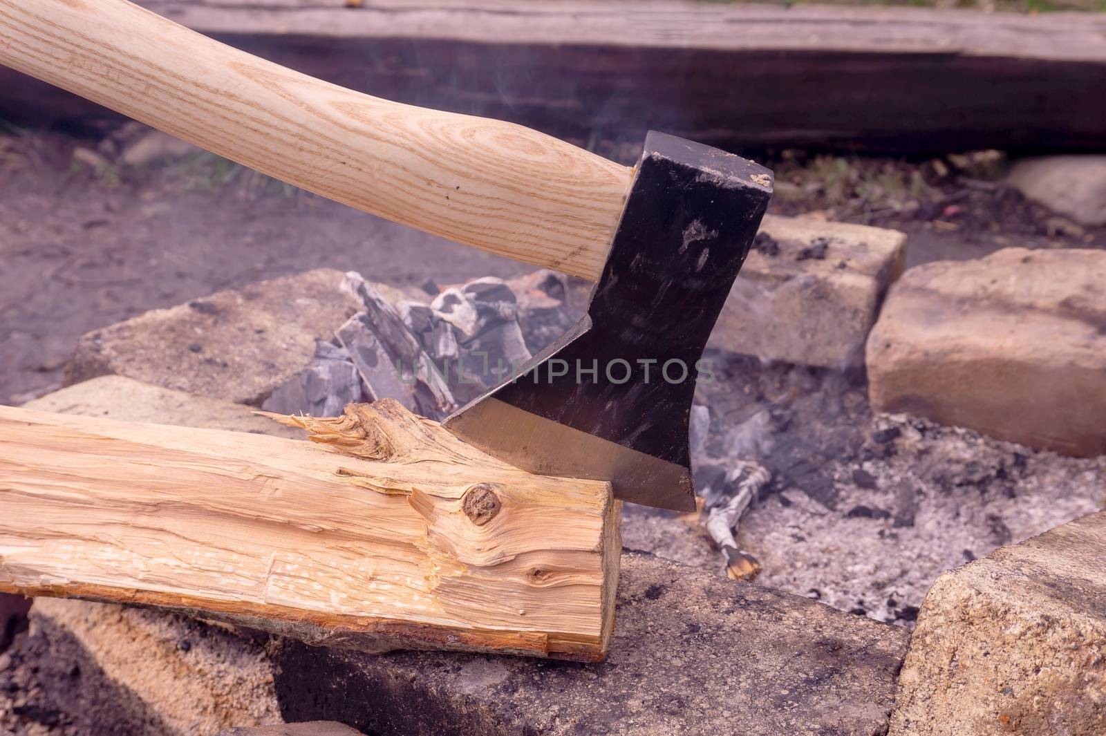 Chopper or axe stuck upright in a tree stump outdoors in a garden or woodland conceptual of an outdoor lifestyle or camping