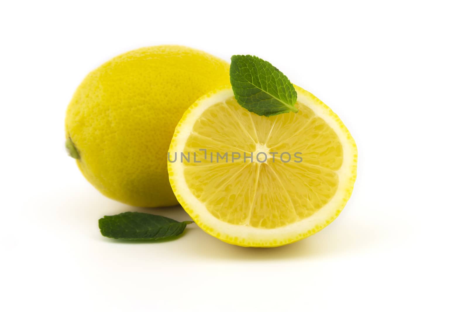 Whole and half sliced lemon and mint leaves isolated on white background