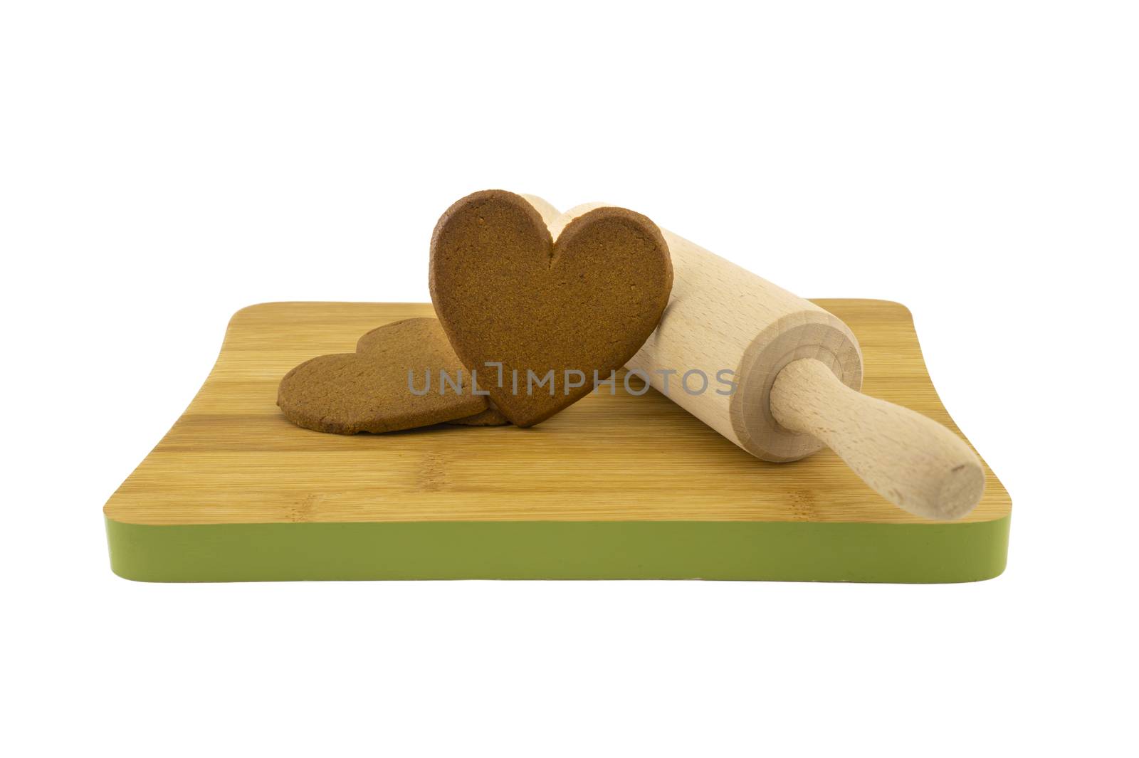 Heart-shaped cookies gift preparation concept with brown biscuits and rolling pin on wooden cutting board isolated on white background