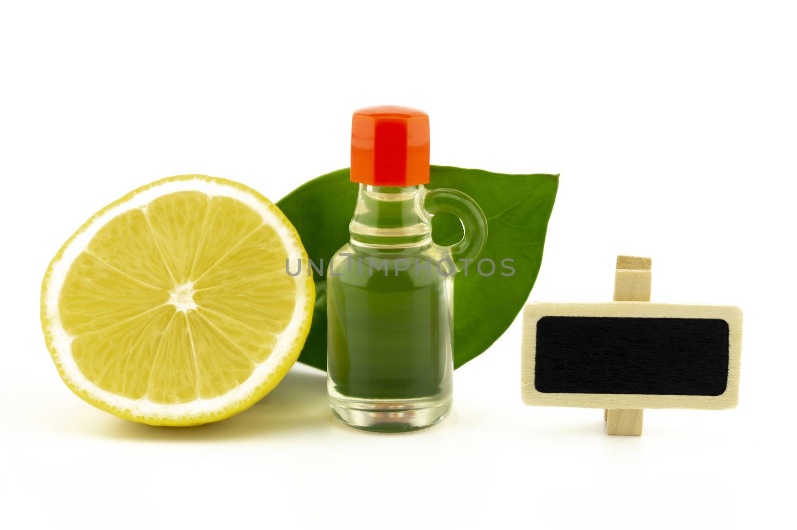 Halved ripe lemon fruit with green leaves alongside a glass decanter and small blank slate or signboard over a white background