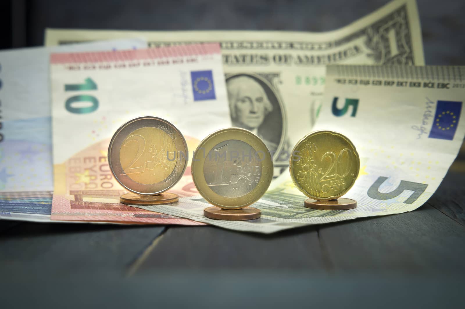 Close-up of Euro and USD cash money with various coins of Euros and cents over banknotes on black wooden table. Strong and stable currency concept with dollar bill and variety of Euro bills