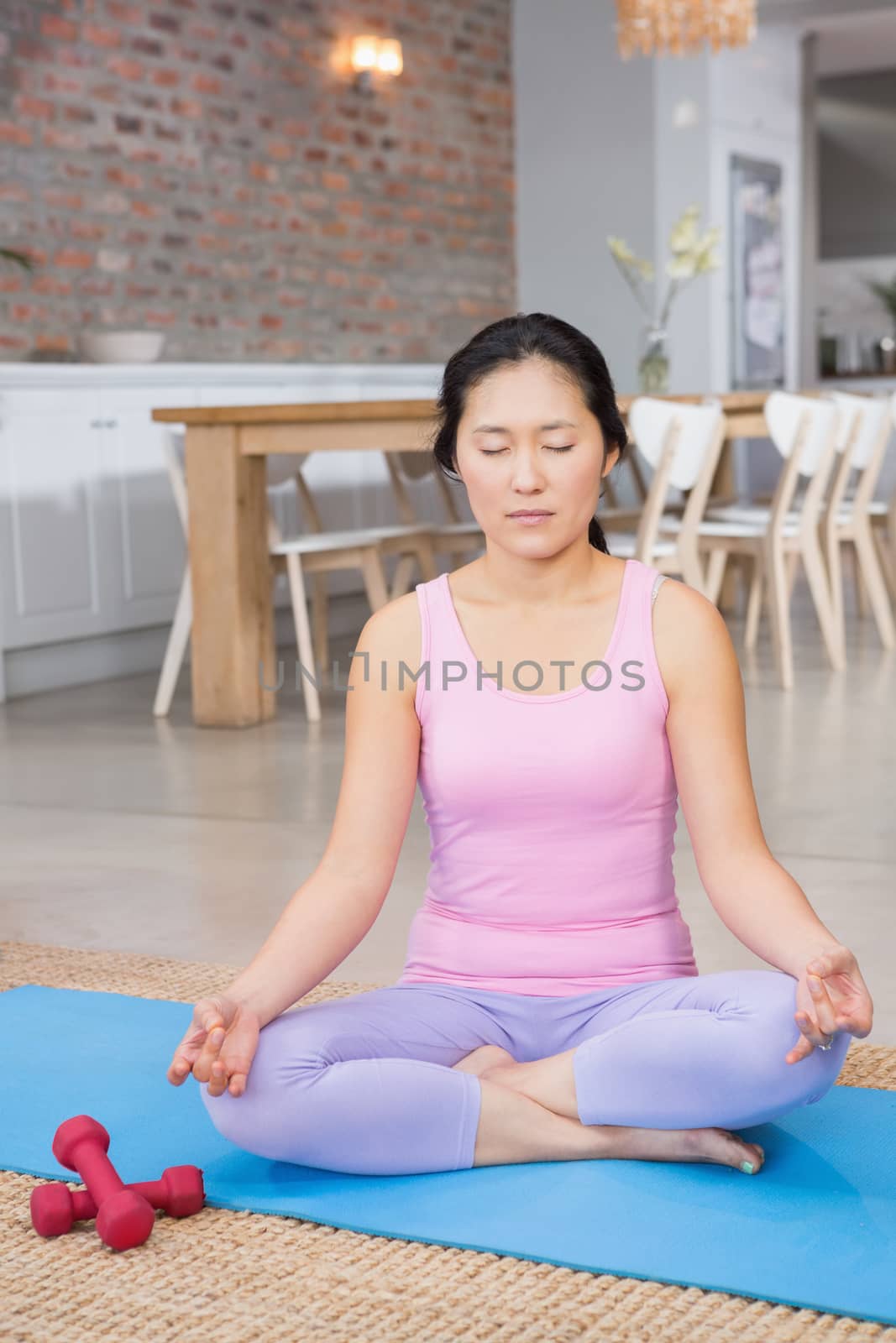 Calm woman doing yoga on mat in living room