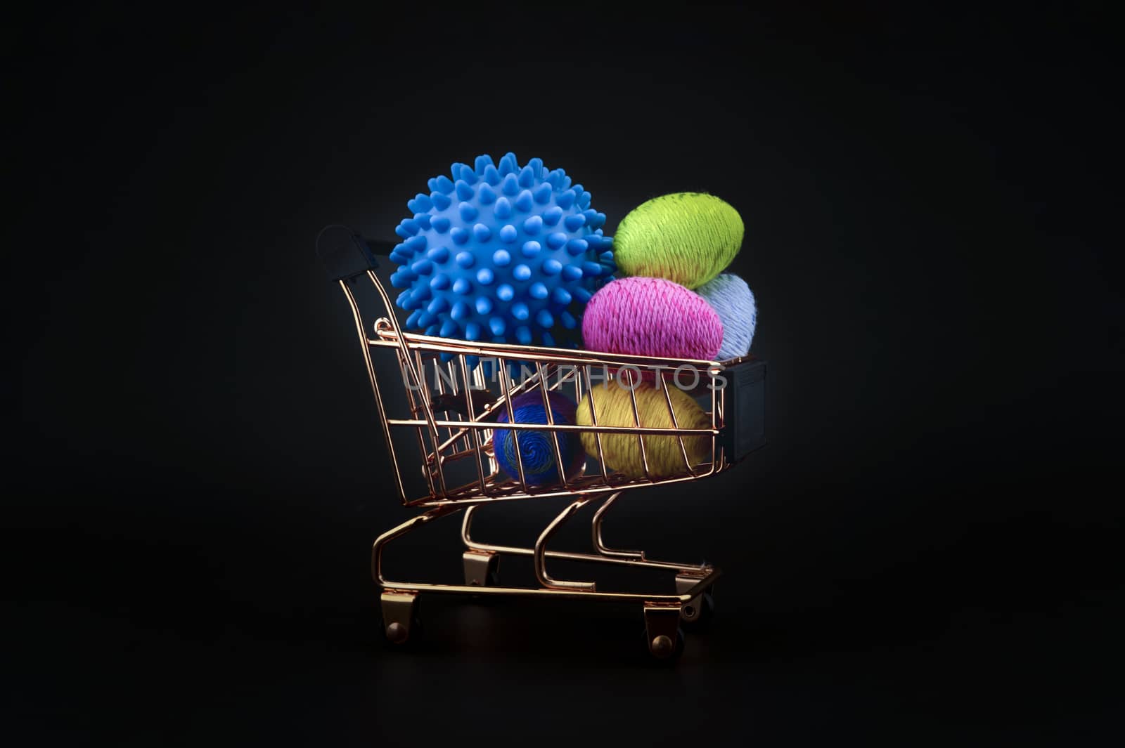 Virus molecule on a shopping cart and creative colorful eggs made from yarn conceptual of the possibility of infection with corona virus or Covid-19 over a black background
