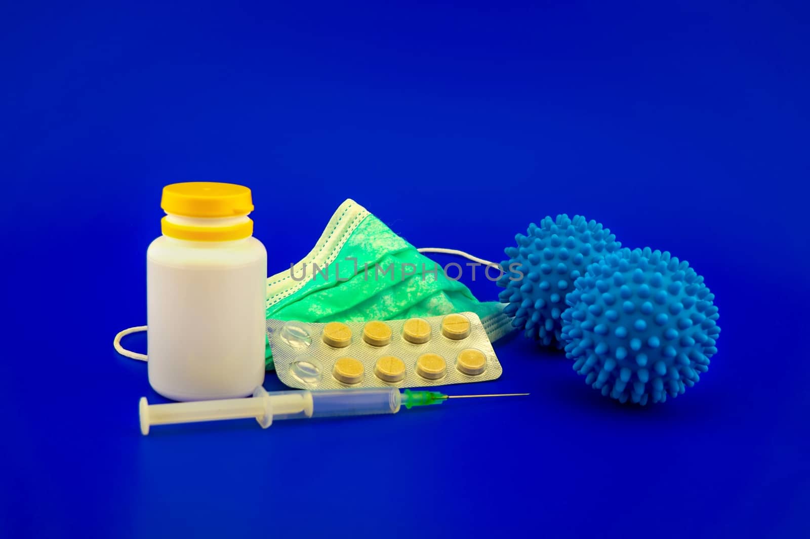 Virus pandemic and possible vaccine concept with surgical mask, hypodermic syringe, pharmaceutical bottle and blue virus molecule in blue toned theme with with copy space