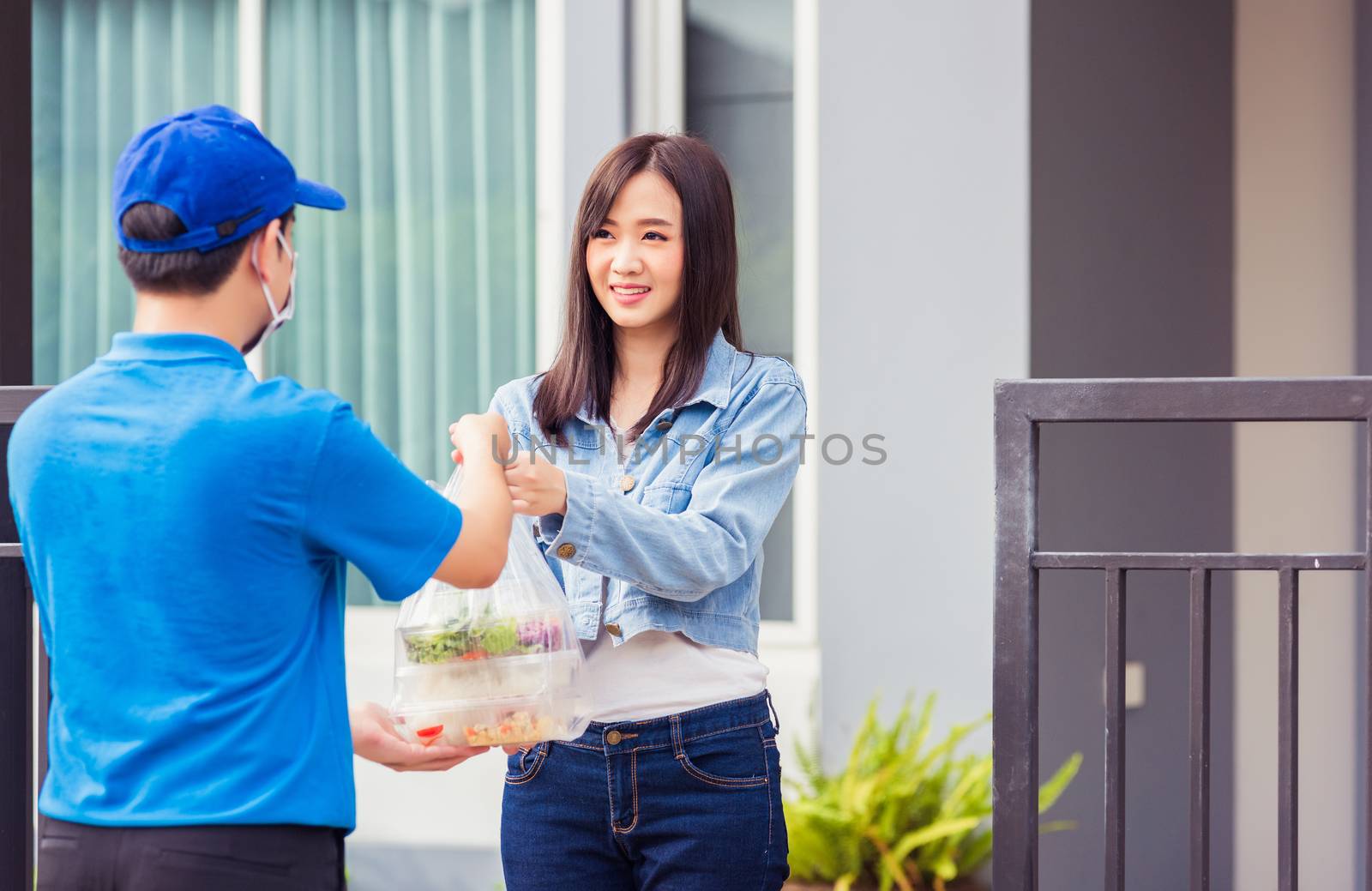 Asian young delivery man wear face mask he making grocery service giving rice food boxes plastic bags to woman customer receiving door at house after pandemic coronavirus, Back to new normal concept