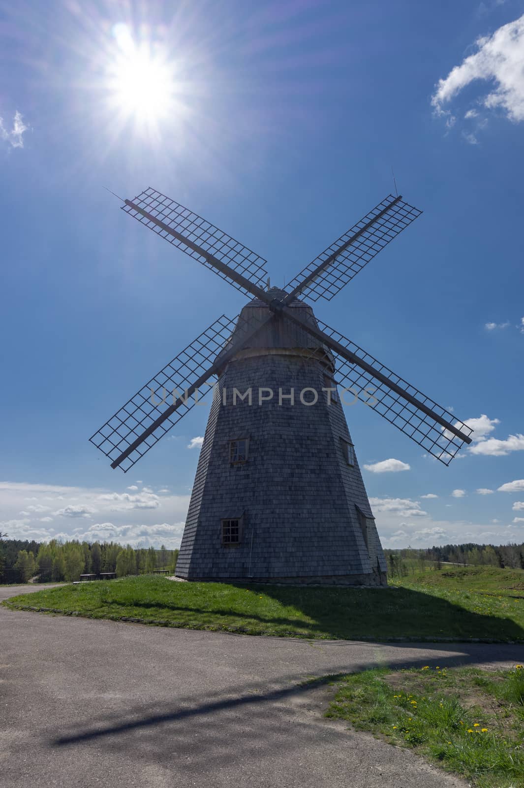 Historic windmill in a lush green field in spring against a sunny blue sky in a scenic landscape