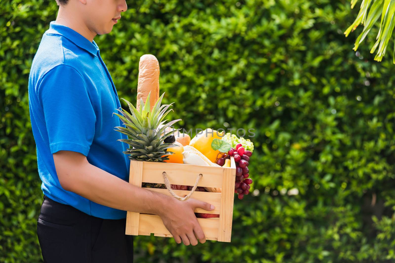 Man farmer wears delivery uniform he holding full fresh vegetabl by Sorapop