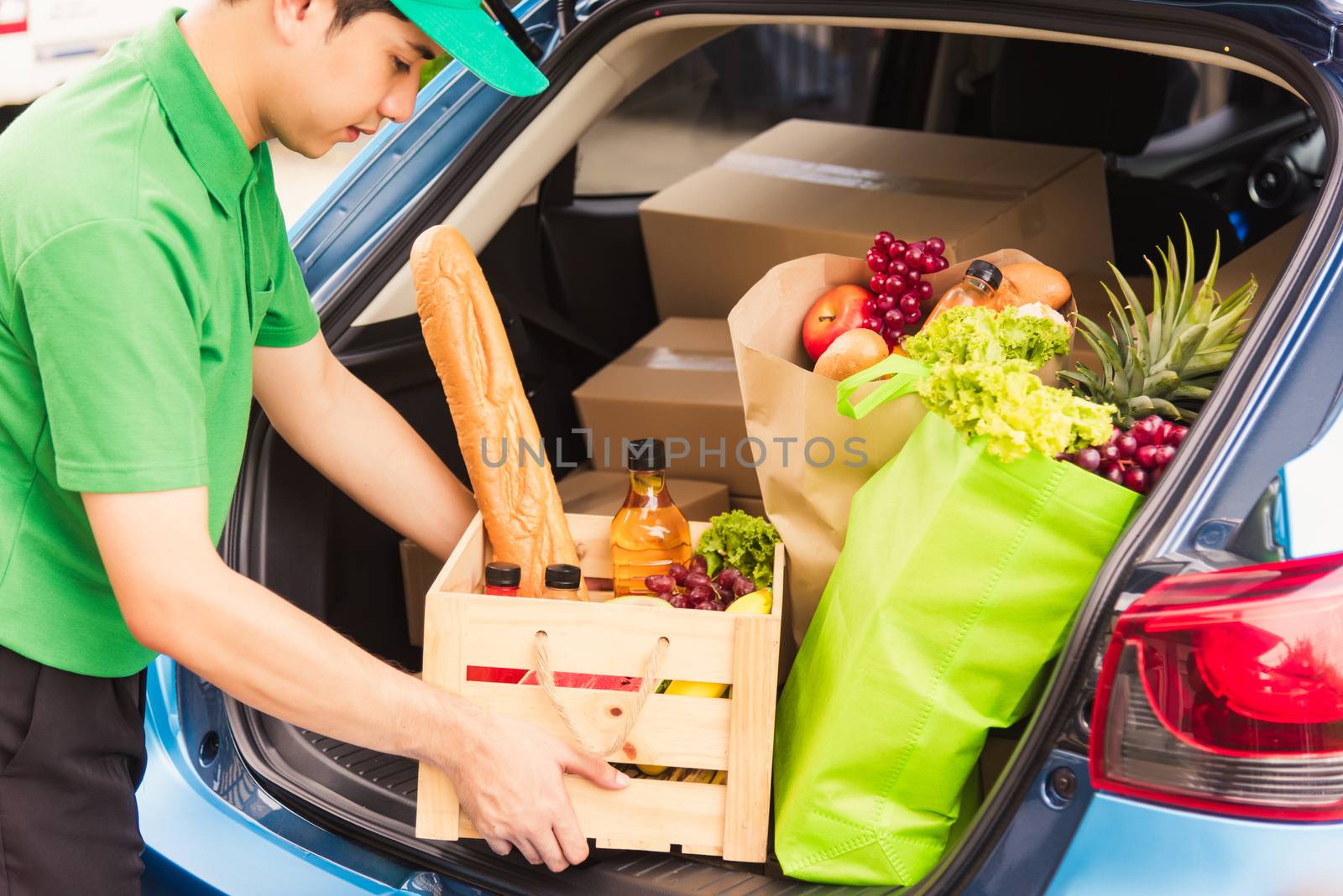 Asian delivery man grocery prepare service giving fresh vegetables food and fruit full in wooden basket on back car to send woman customer at door home after pandemic coronavirus, Back to new normal