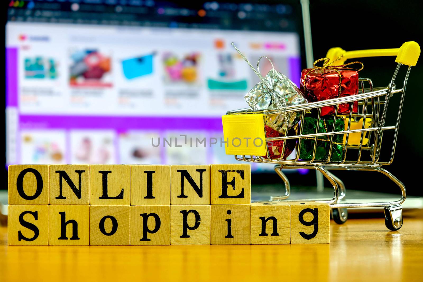 Wooden Alphabet "online shopping" and shopping cart in front of the Blured Shopping Online Website