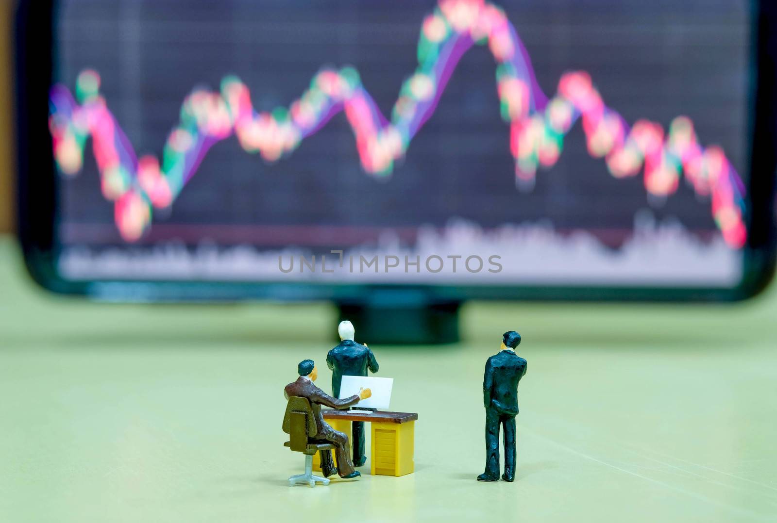 Miniature figure business people or Stock Trader looking at Blur Stock board for Graph Analysis