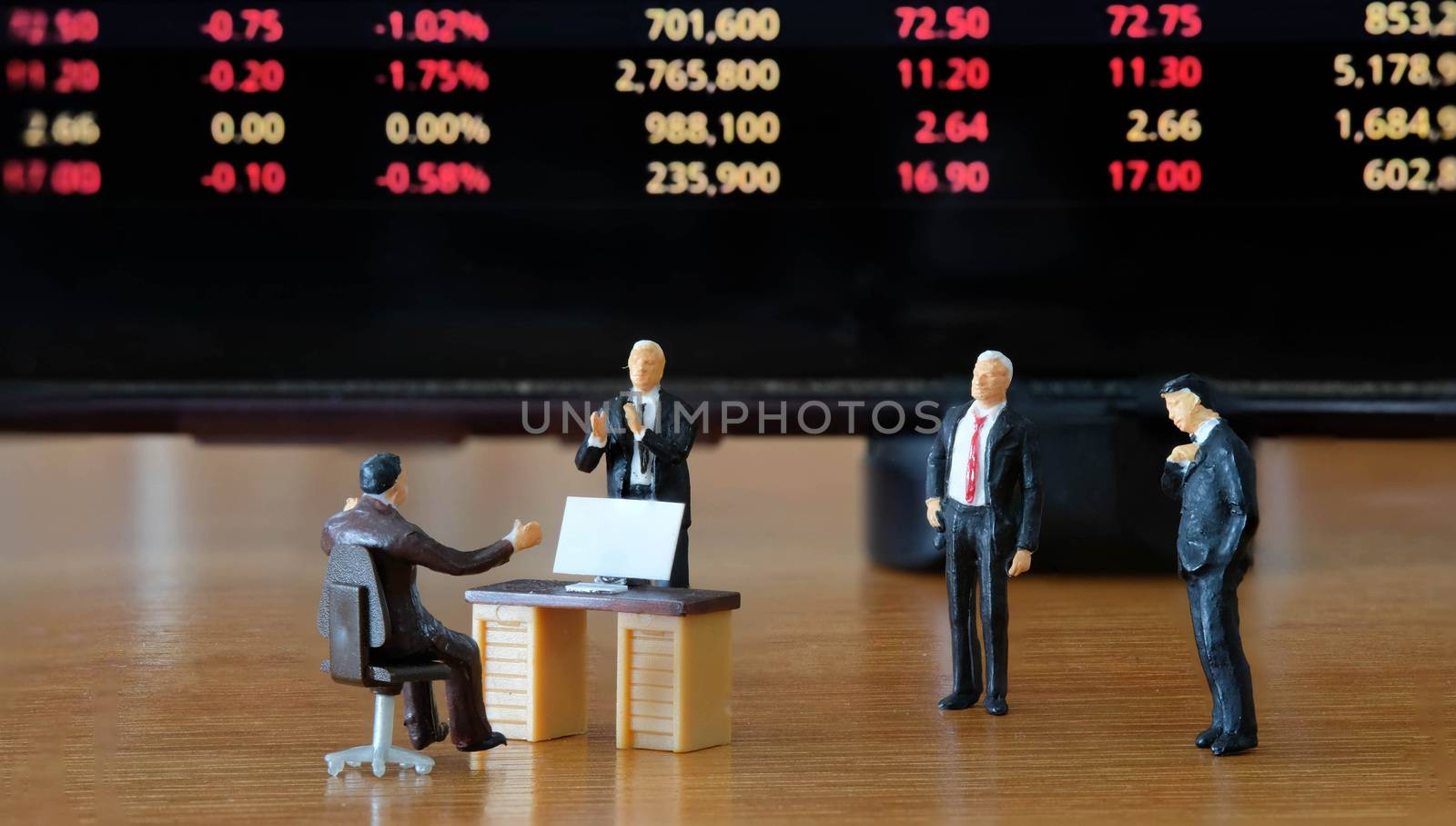 Miniature figure business people or Stock Trader looking at Blur Price Stock Ticker board for Graph Analysis