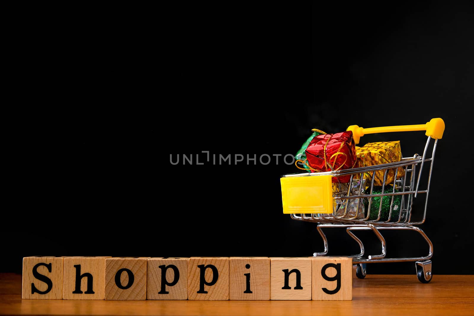 Wooden Alphabet words "shopping" and shopping cart with full of presents or gifts  Isolated on Black Background