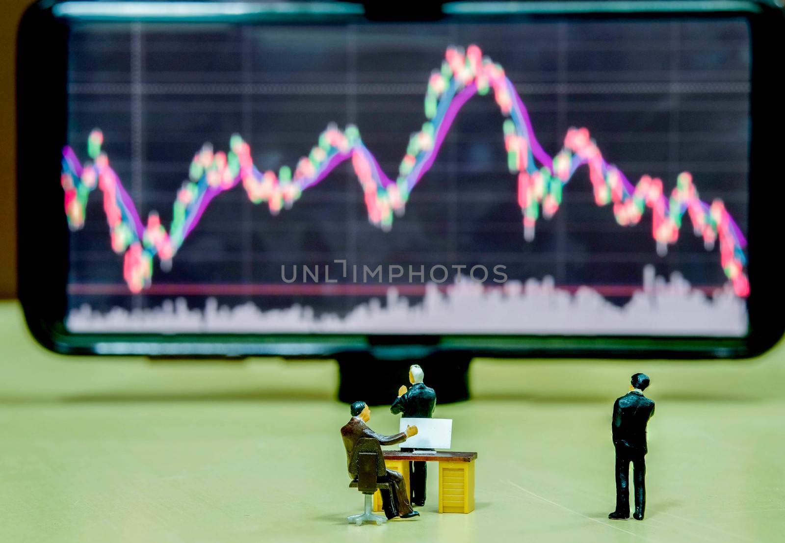 Miniature figure business people or Stock Trader looking at Blur Stock board for Graph Analysis